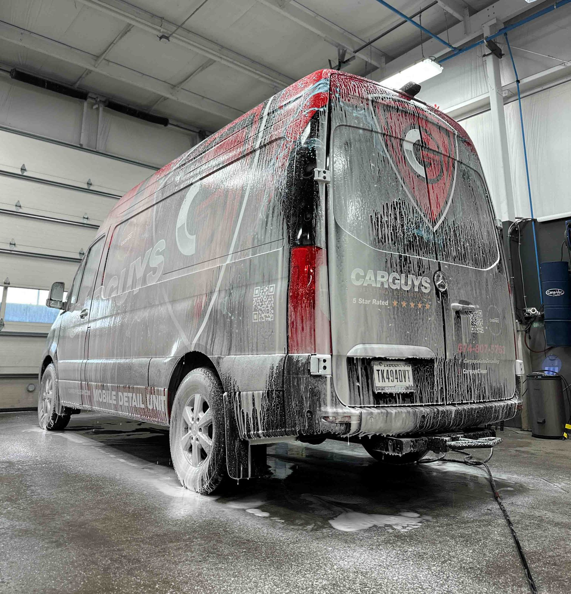 A person wearing black gloves is polishing the hood of a red car.