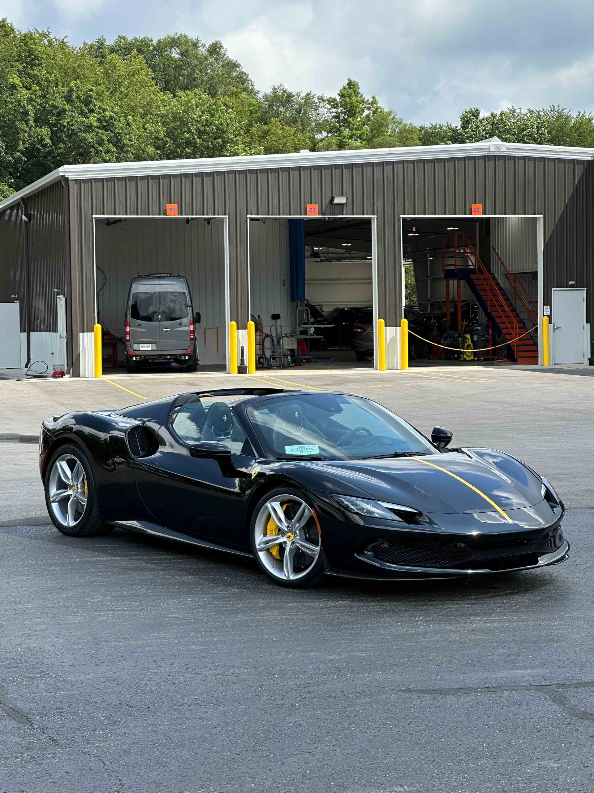 A person wearing black gloves is polishing a black car