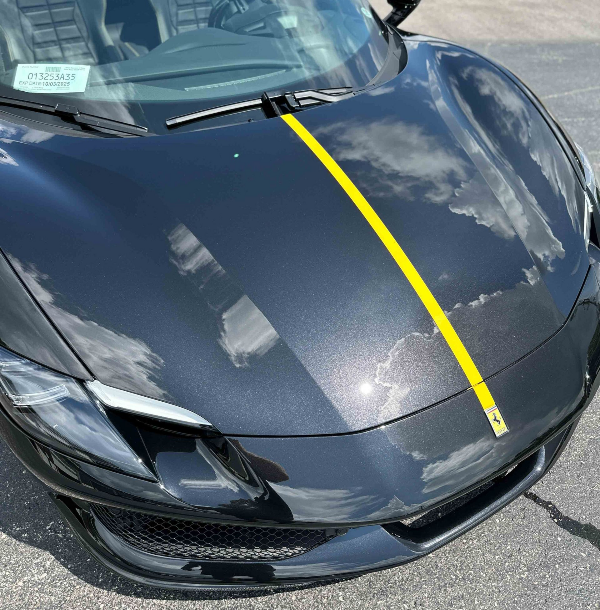 A person wearing black gloves is polishing the hood of a red car.