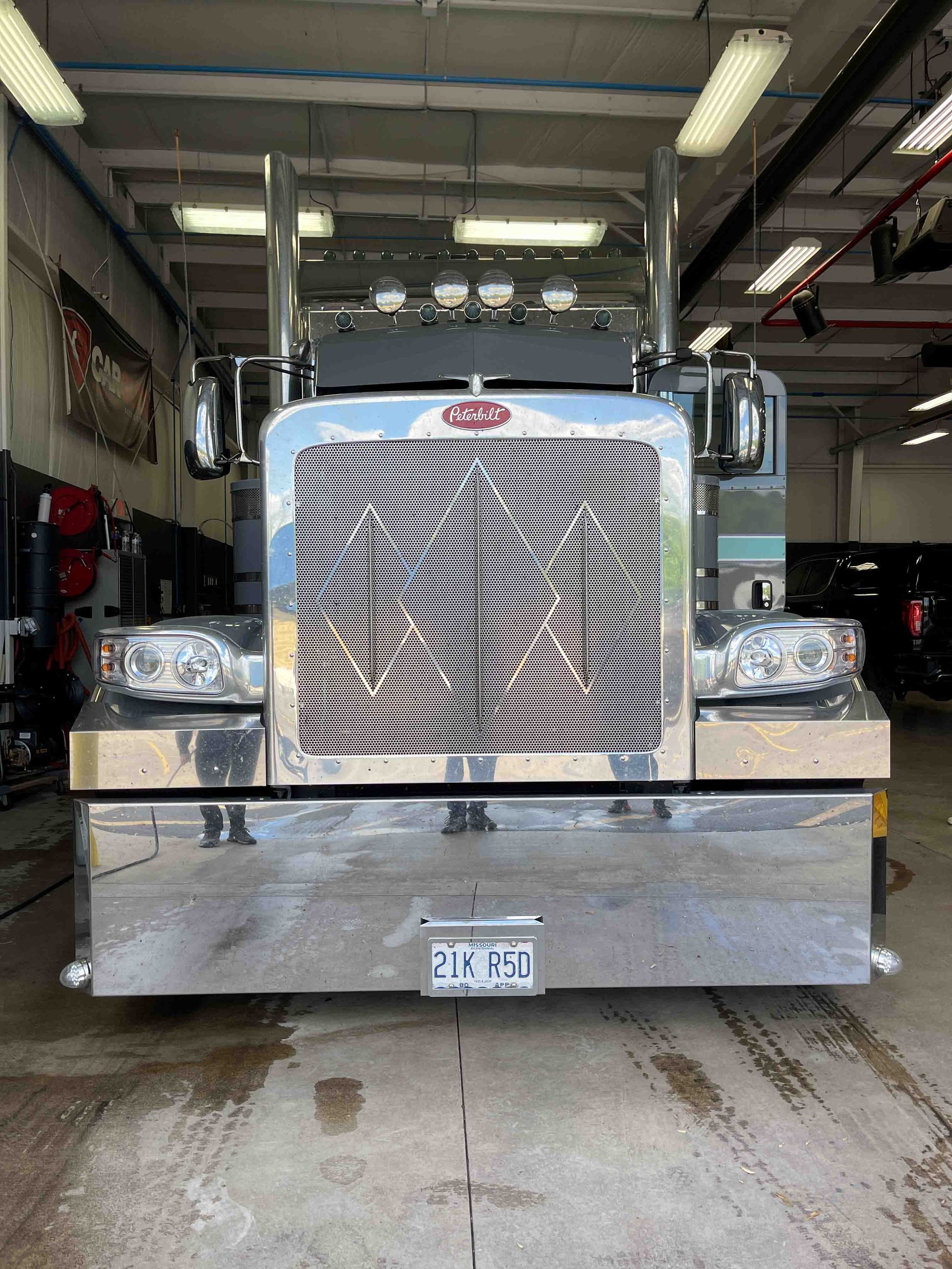 A person wearing black gloves is polishing a black car