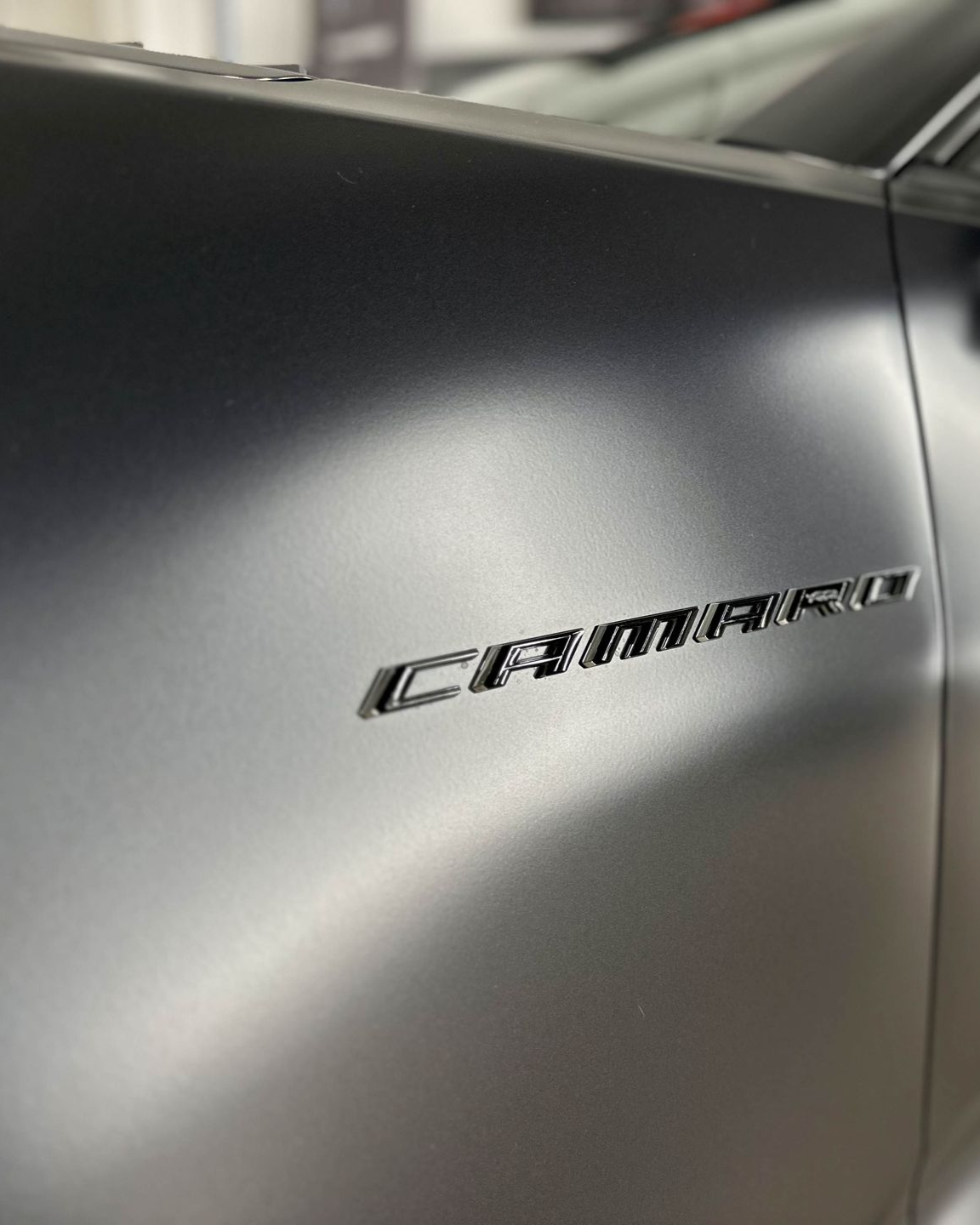 A person wearing black gloves is polishing a black car