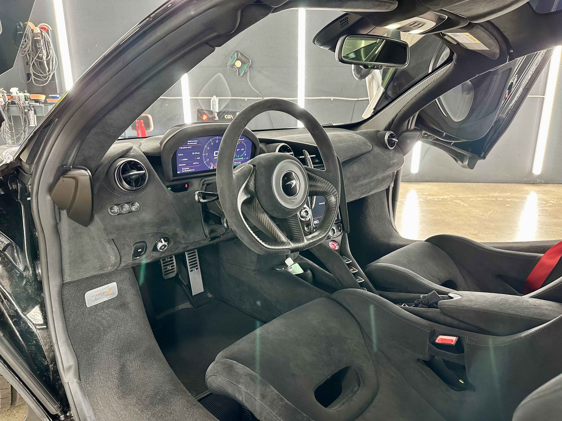 Black car interior with open door, showing steering wheel and dashboard details.