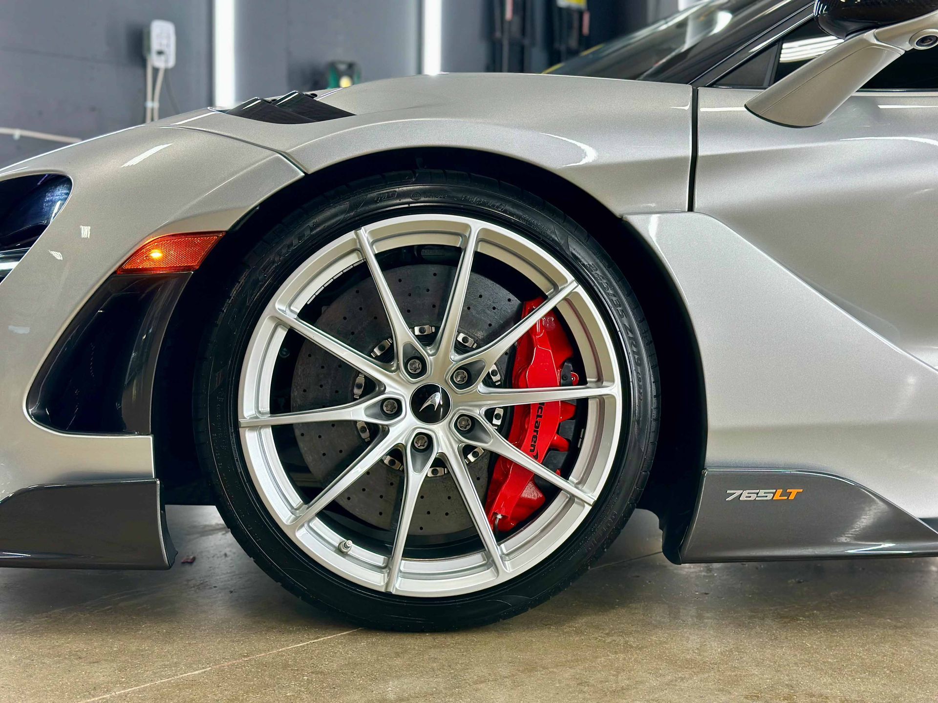 Silver McLaren car wheel with a red brake caliper.