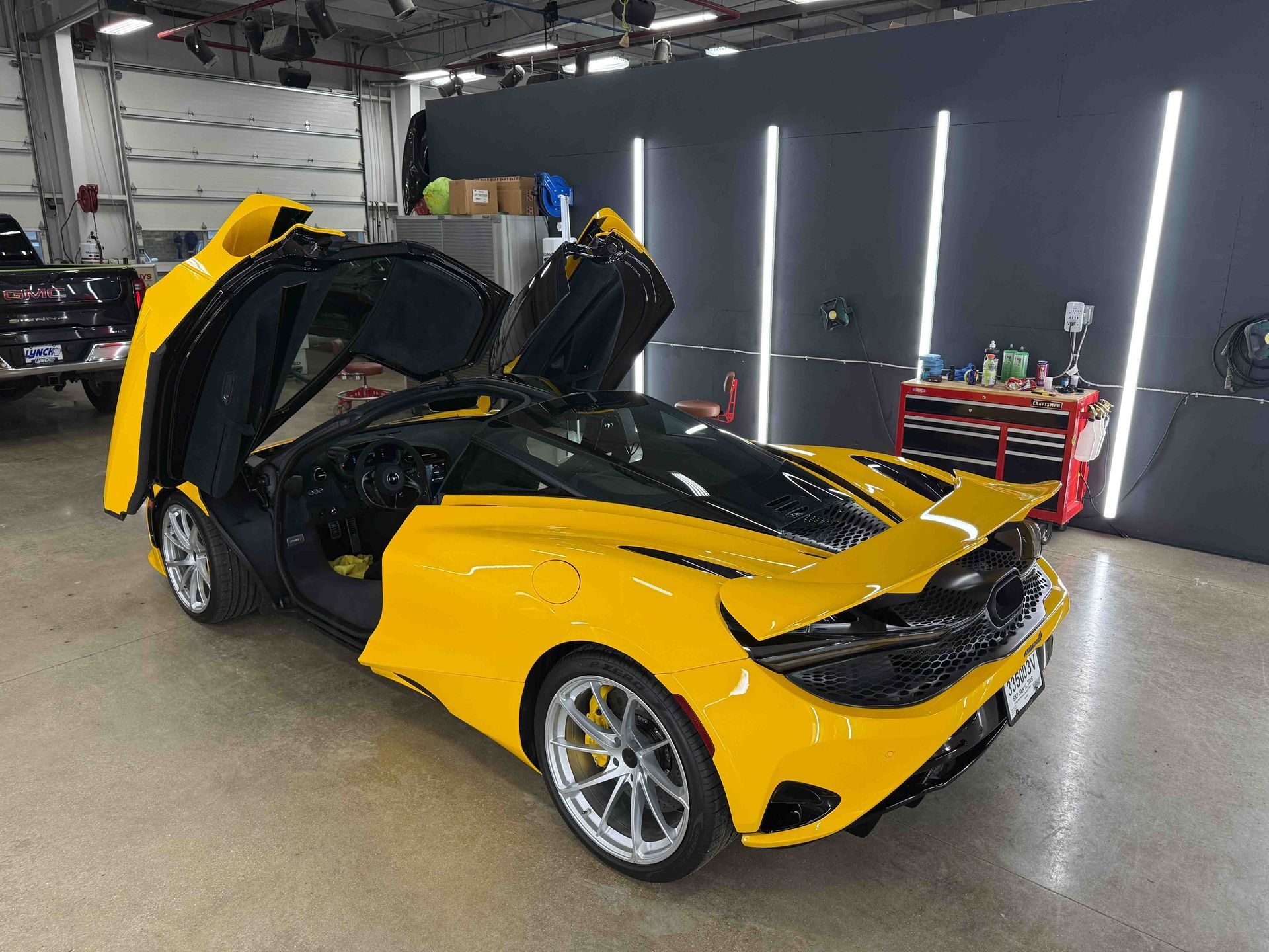 Yellow McLaren sports car with doors open in a garage.