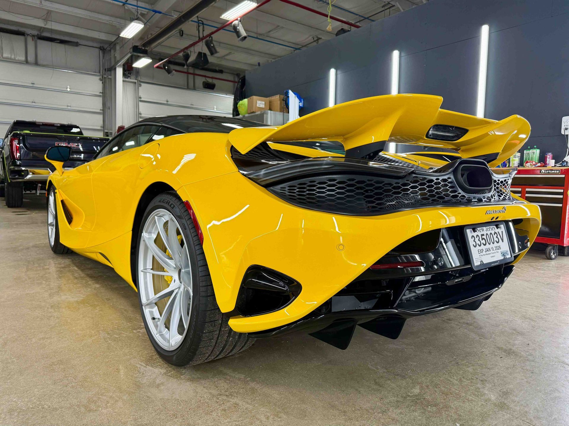 Yellow McLaren sports car with large rear wing, parked inside a garage.