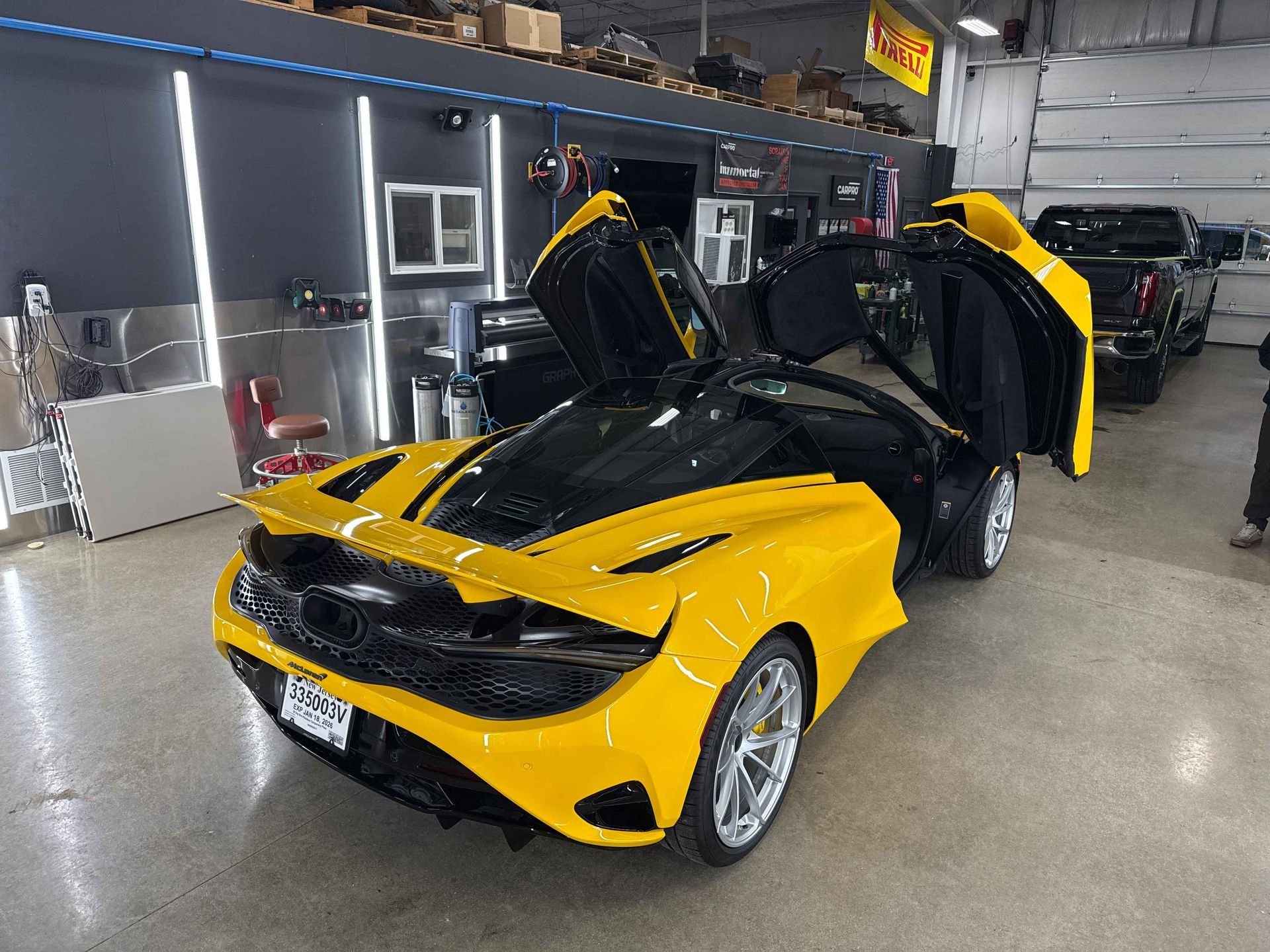 Yellow and black McLaren sports car with doors open in a garage.