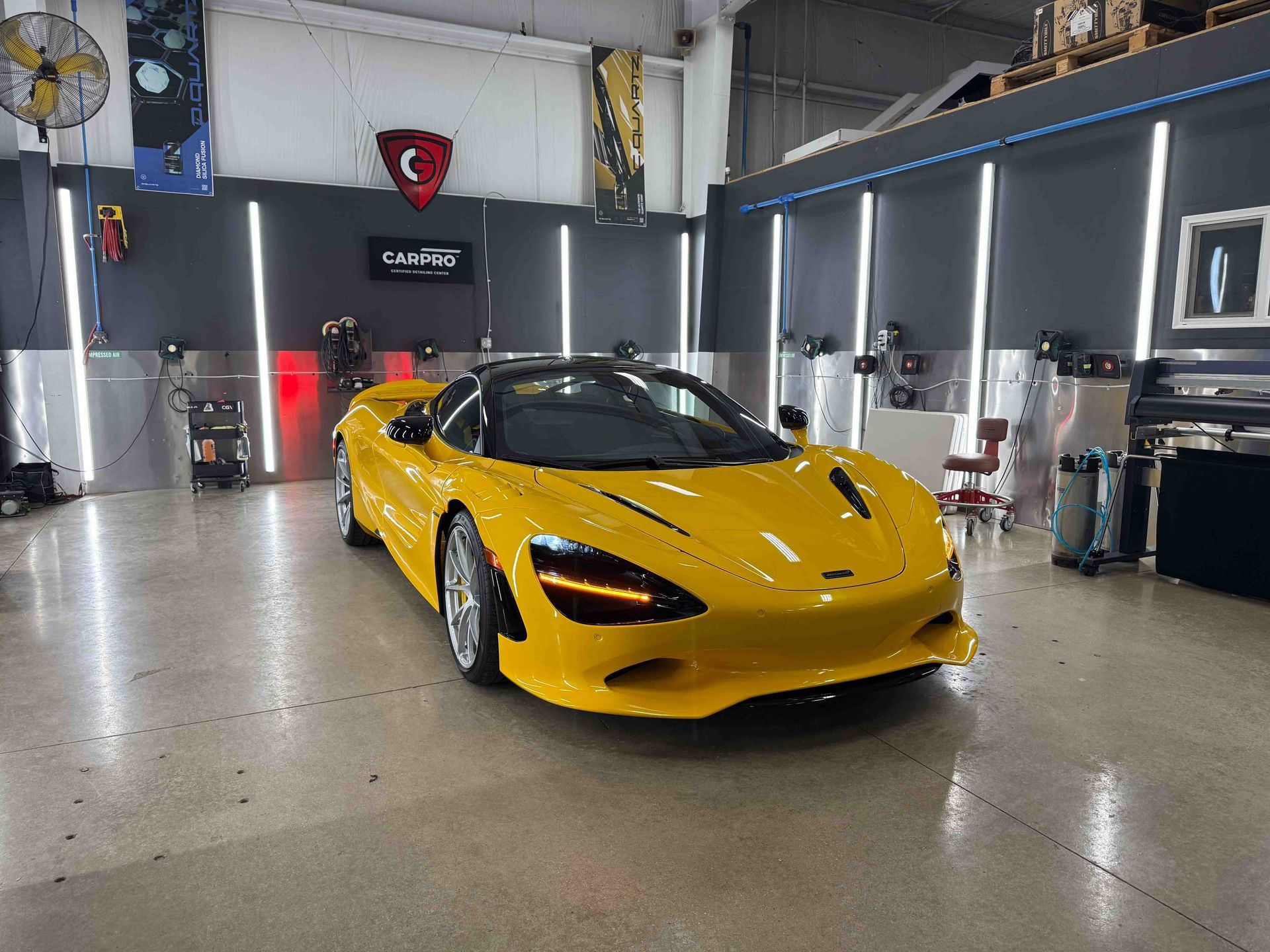 Yellow McLaren sports car in a garage with overhead lighting.