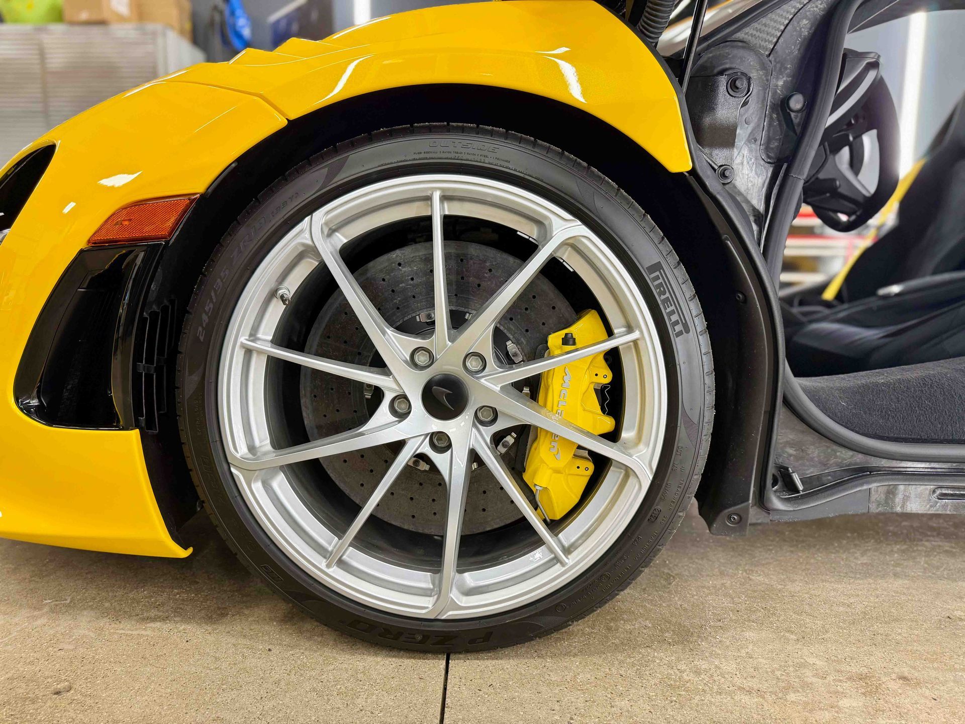 Yellow sports car with a silver wheel, yellow brake caliper, and an open door.