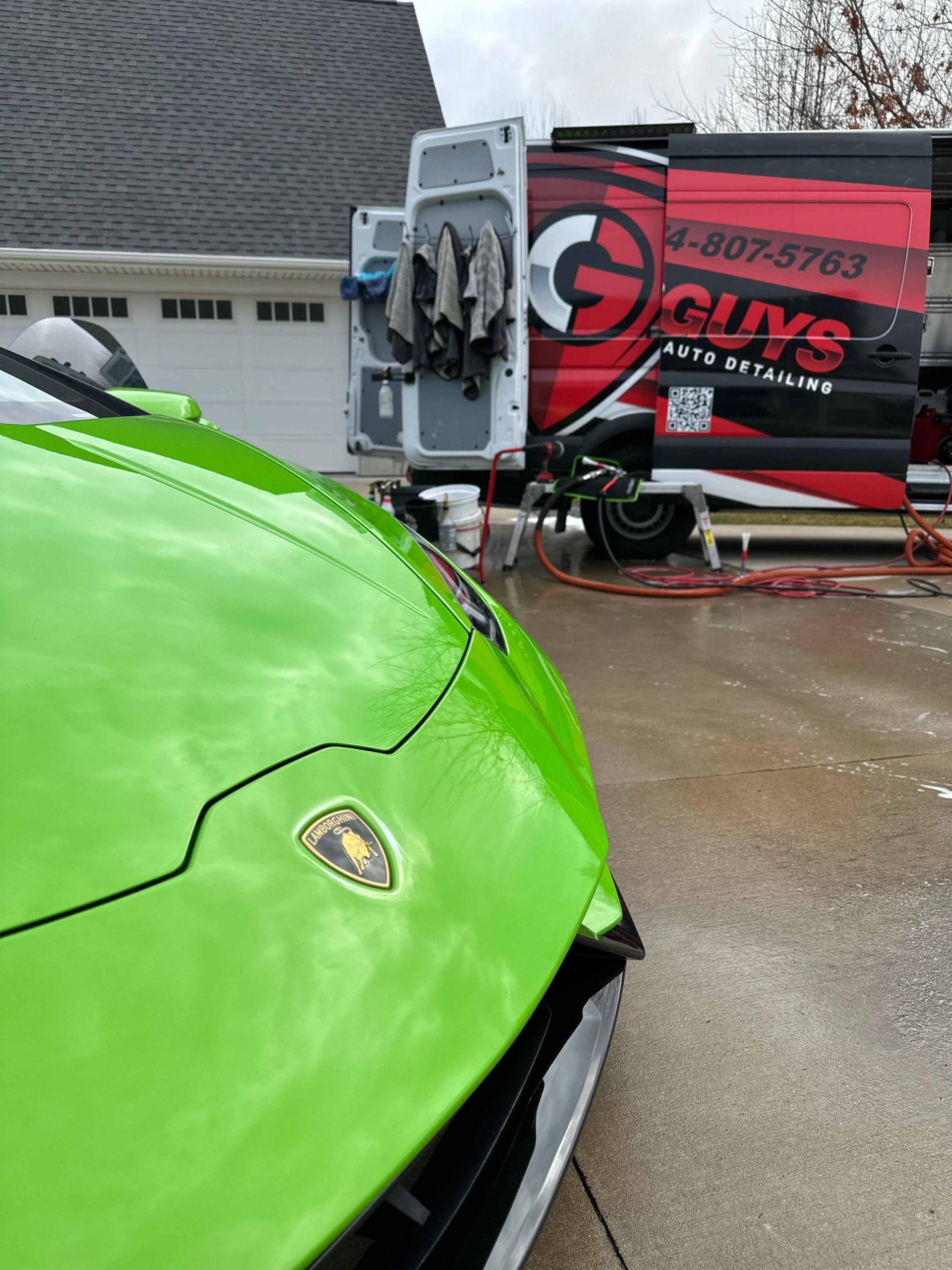 Green sports car being detailed by a van with the 