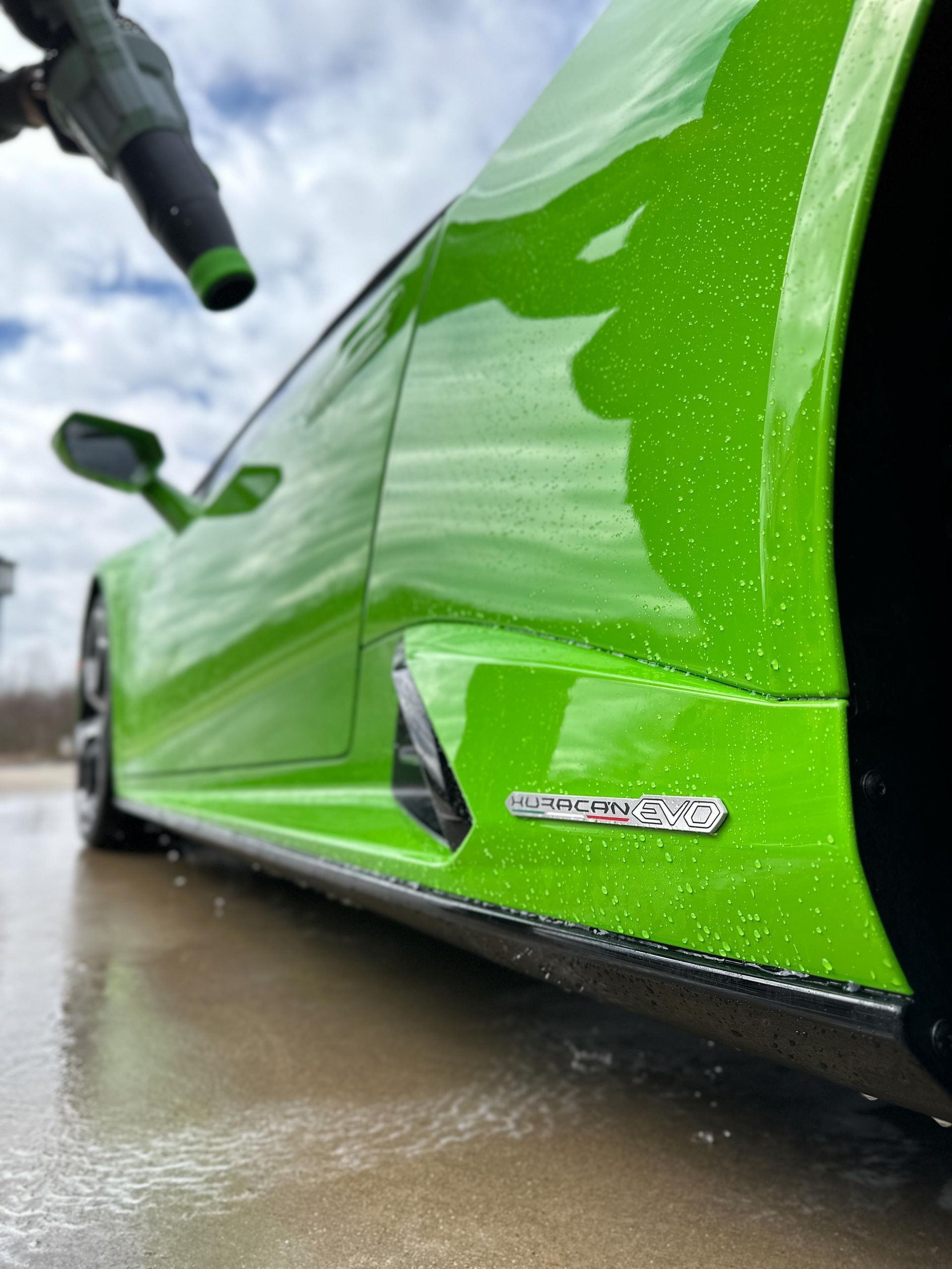 Green Lamborghini being dried with a blower. Wet exterior and silver 