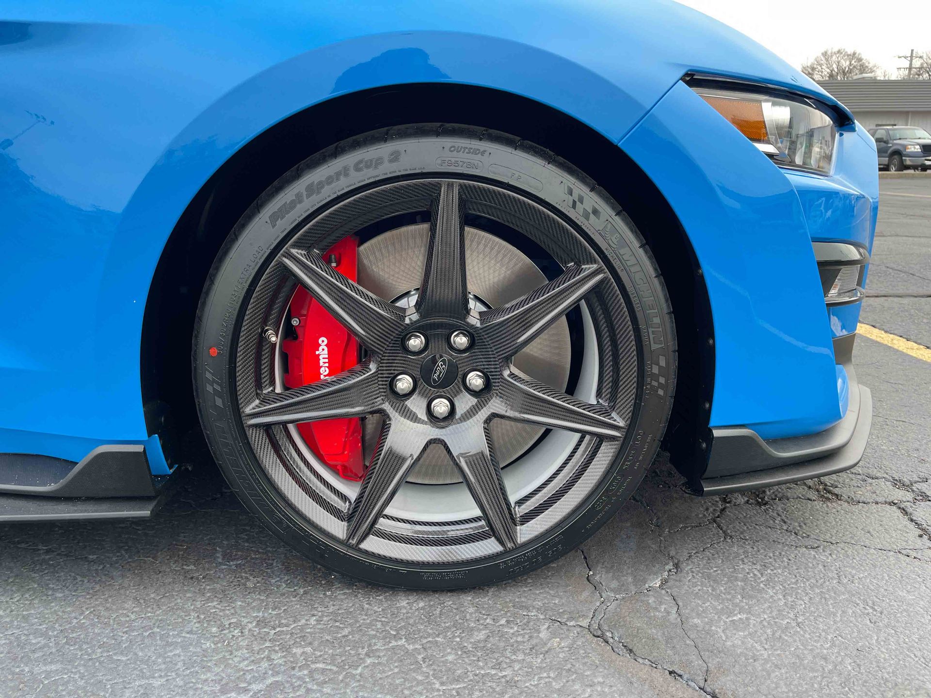Blue sports car front wheel with dark gray rim and red brake caliper.