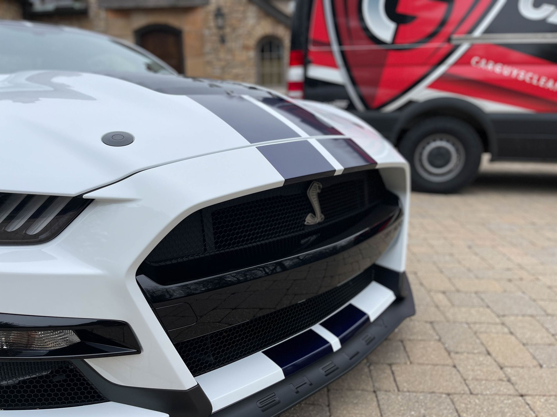 White Ford Mustang Shelby with blue racing stripes, parked, and a 