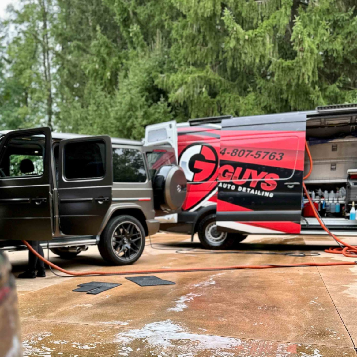 A person wearing black gloves is polishing the hood of a red car.