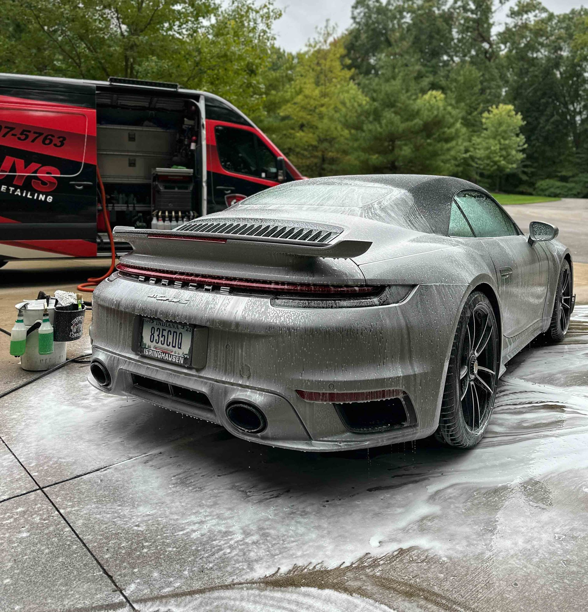A person wearing black gloves is polishing the hood of a red car.