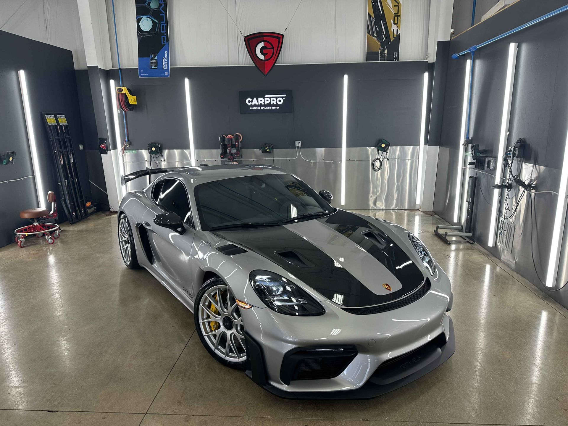 Silver Porsche with black accents in a car detailing shop.