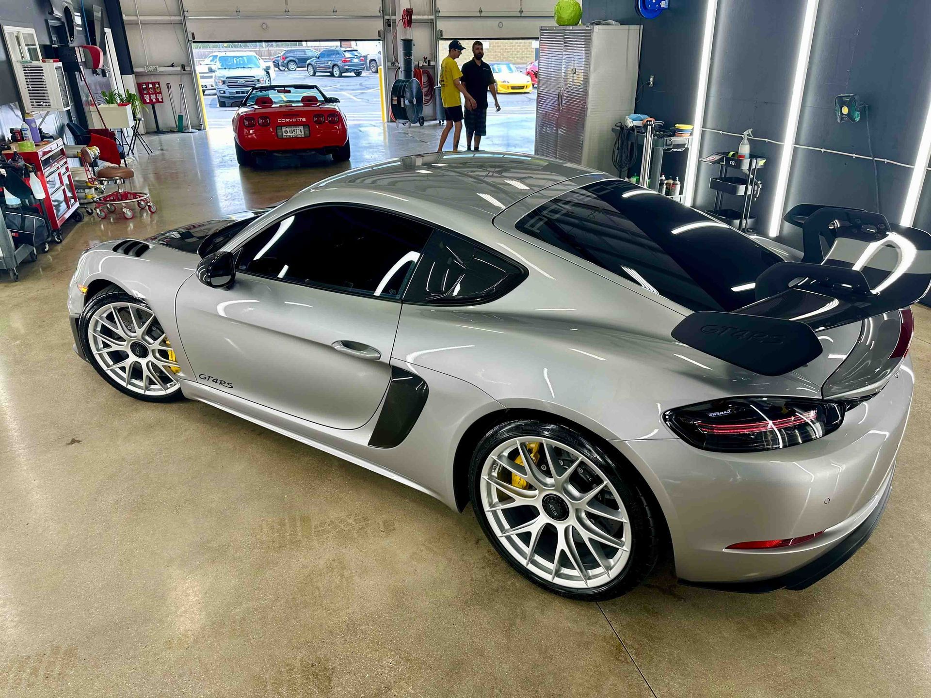 Silver Porsche sports car with black spoiler, parked in a shop.