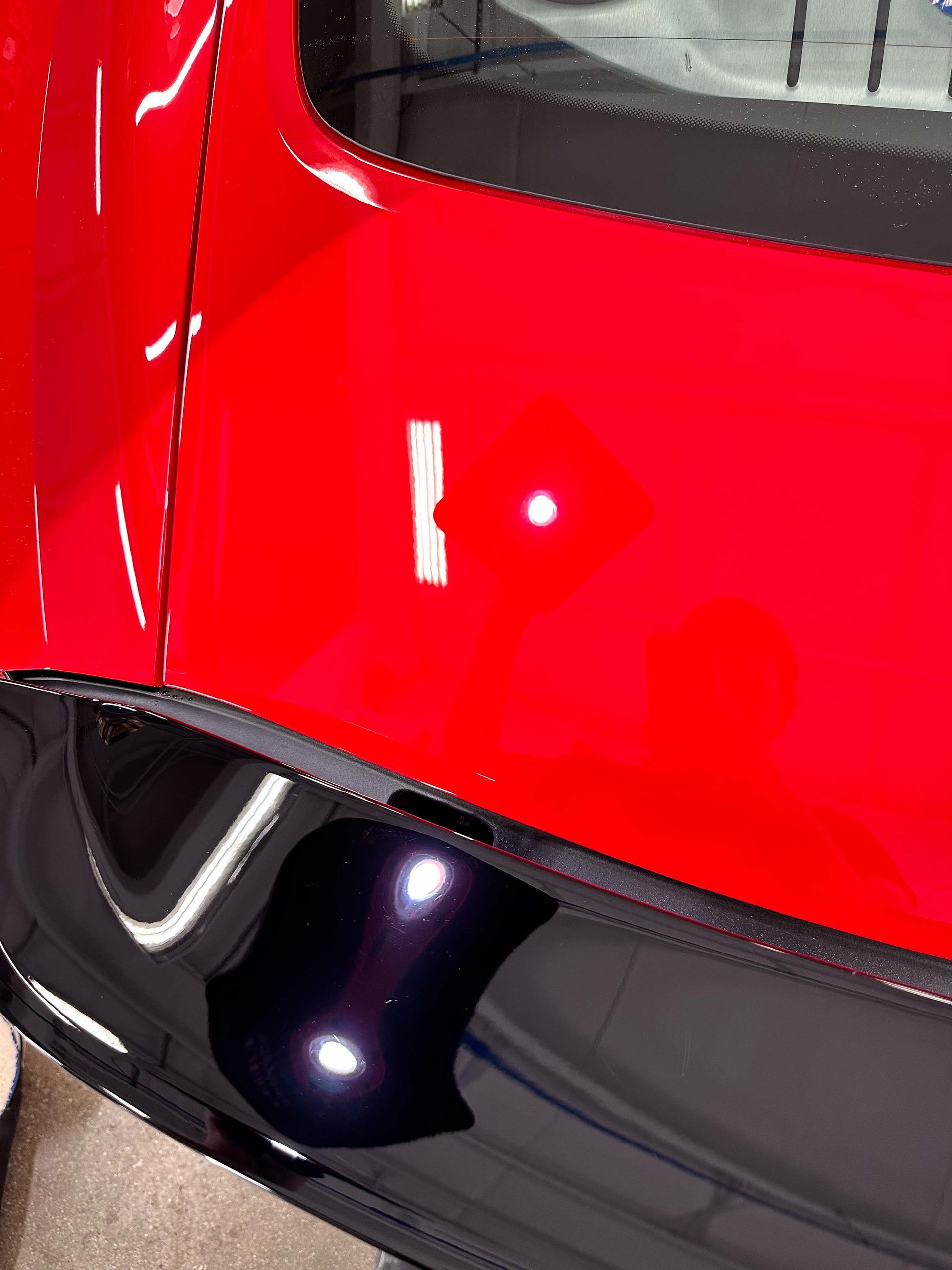 Red and black car body with a white light reflection.