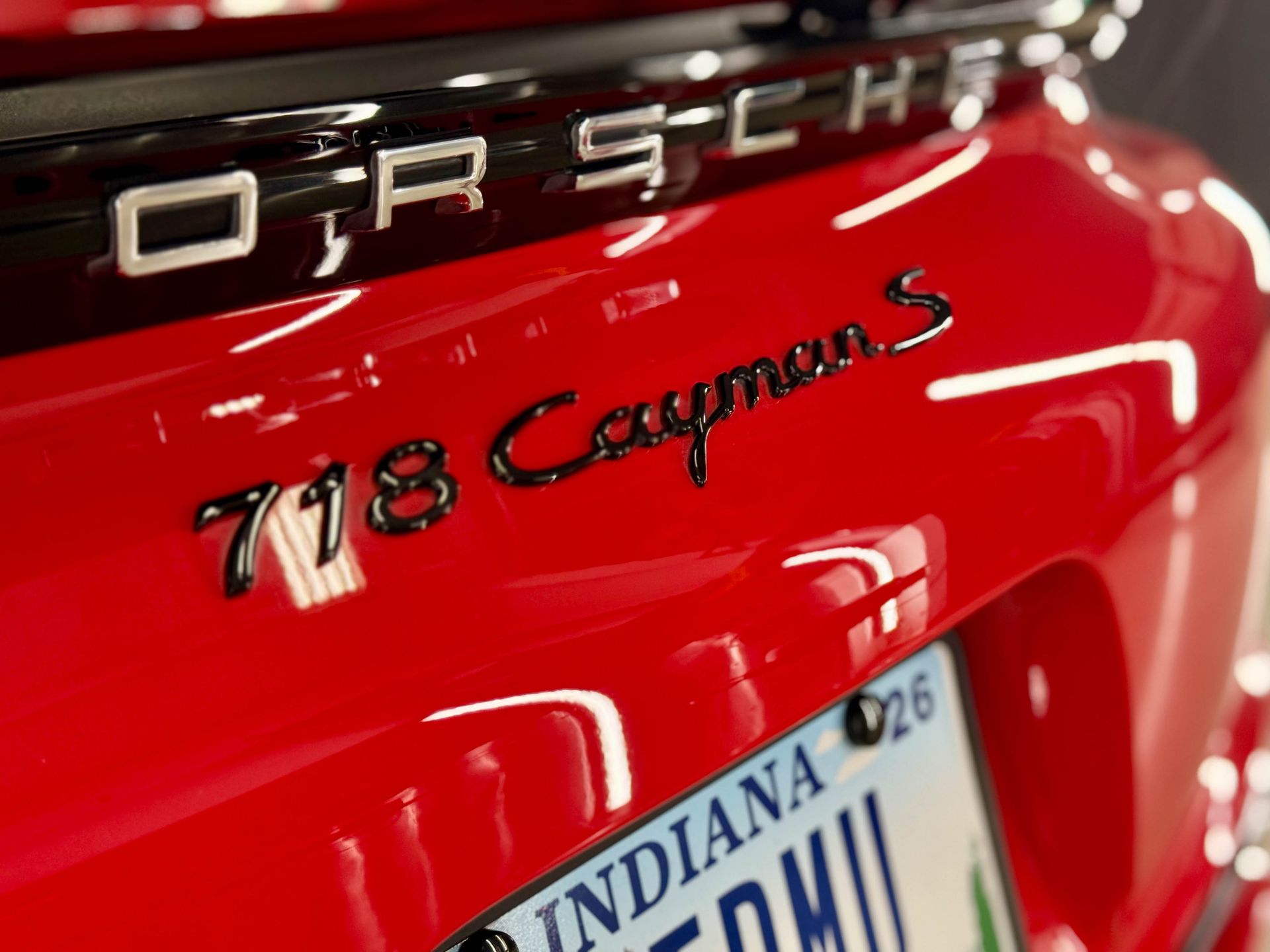 Red Porsche 718 Cayman S rear with black lettering, Indiana license plate.