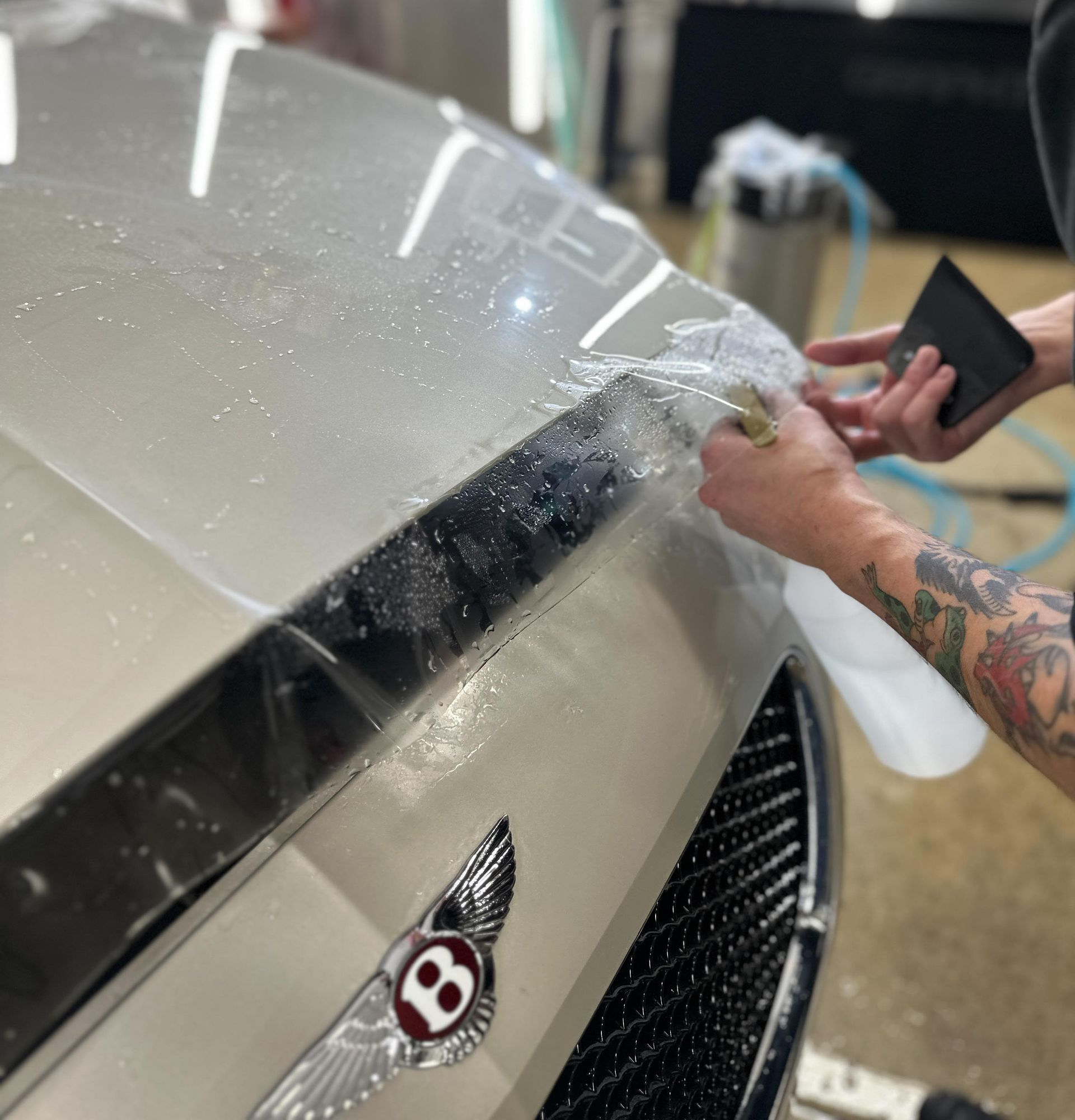 A person wearing black gloves is polishing the hood of a red car.