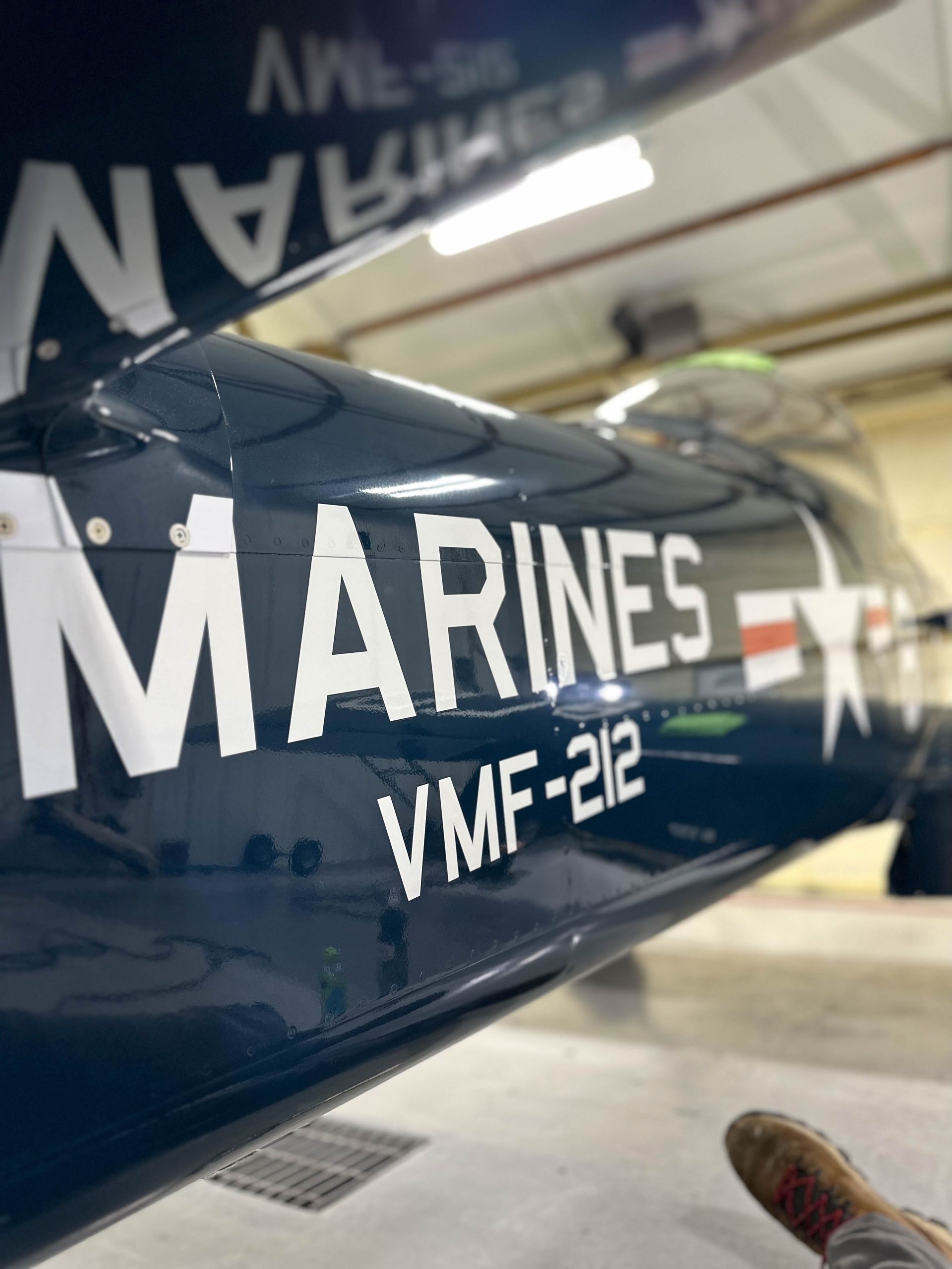 A person wearing black gloves is polishing a black car