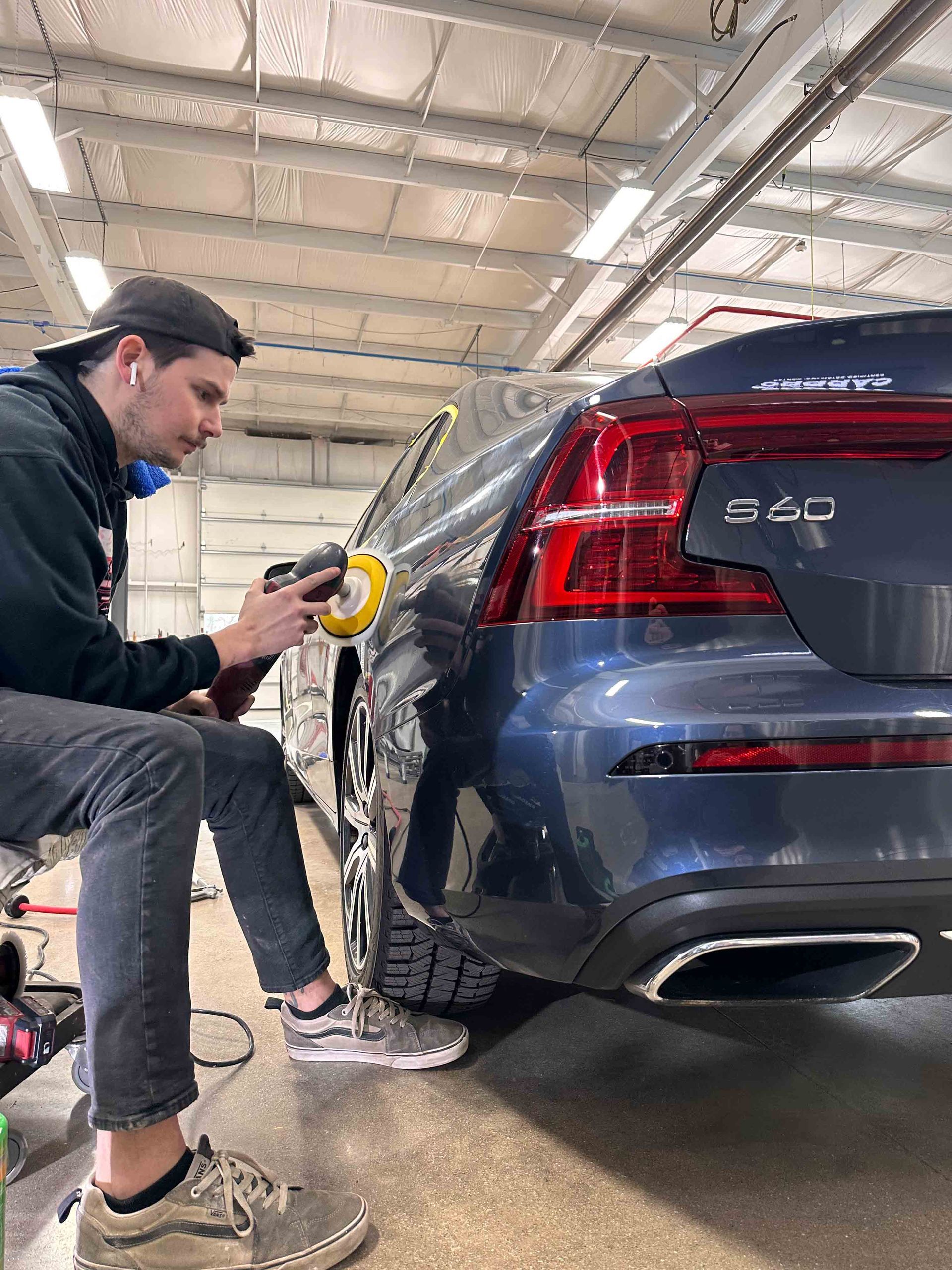 A person is applying a clear film to the hood of a car.