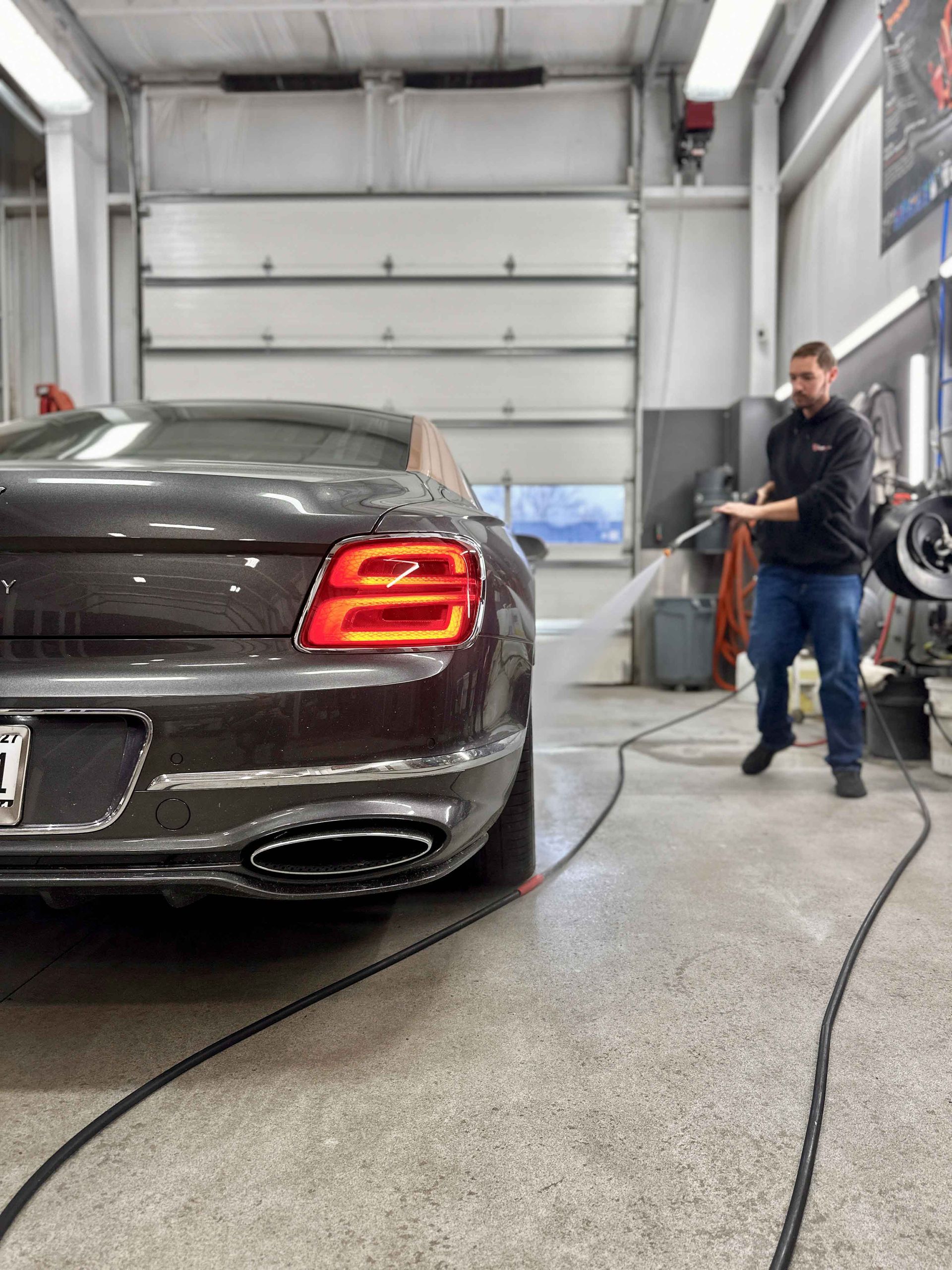 A car is covered in plastic wrap in a garage.