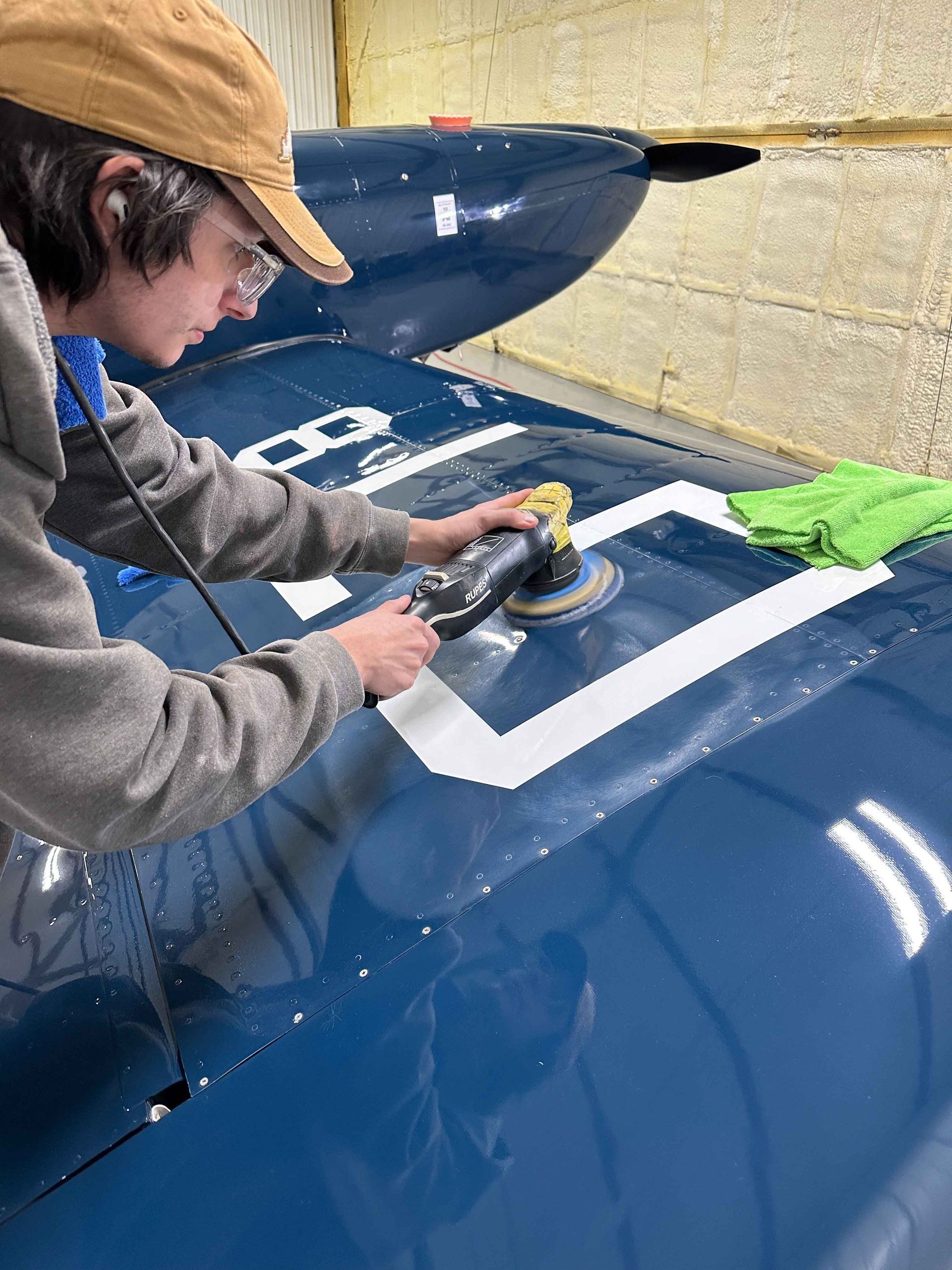 A man is cleaning the wheel of a black car with a sponge.