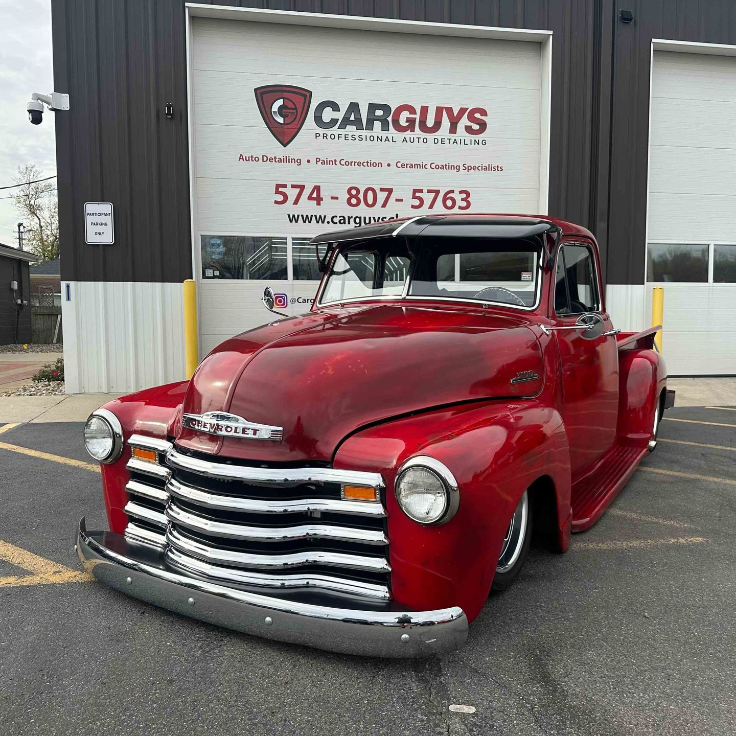 Red vintage Chevrolet pickup truck parked in front of a garage, with 