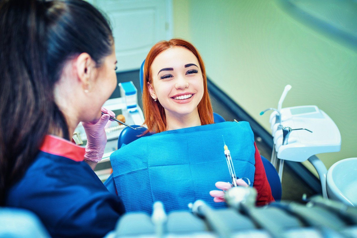 A woman is sitting in a dental chair talking to a dentist.