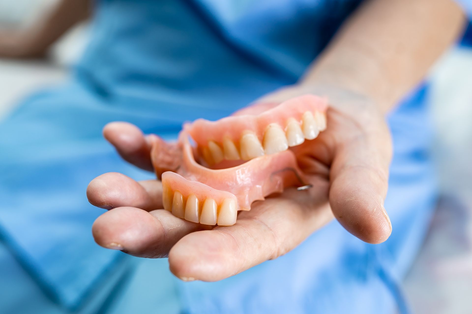 A person is holding a pair of dentures in their hand.