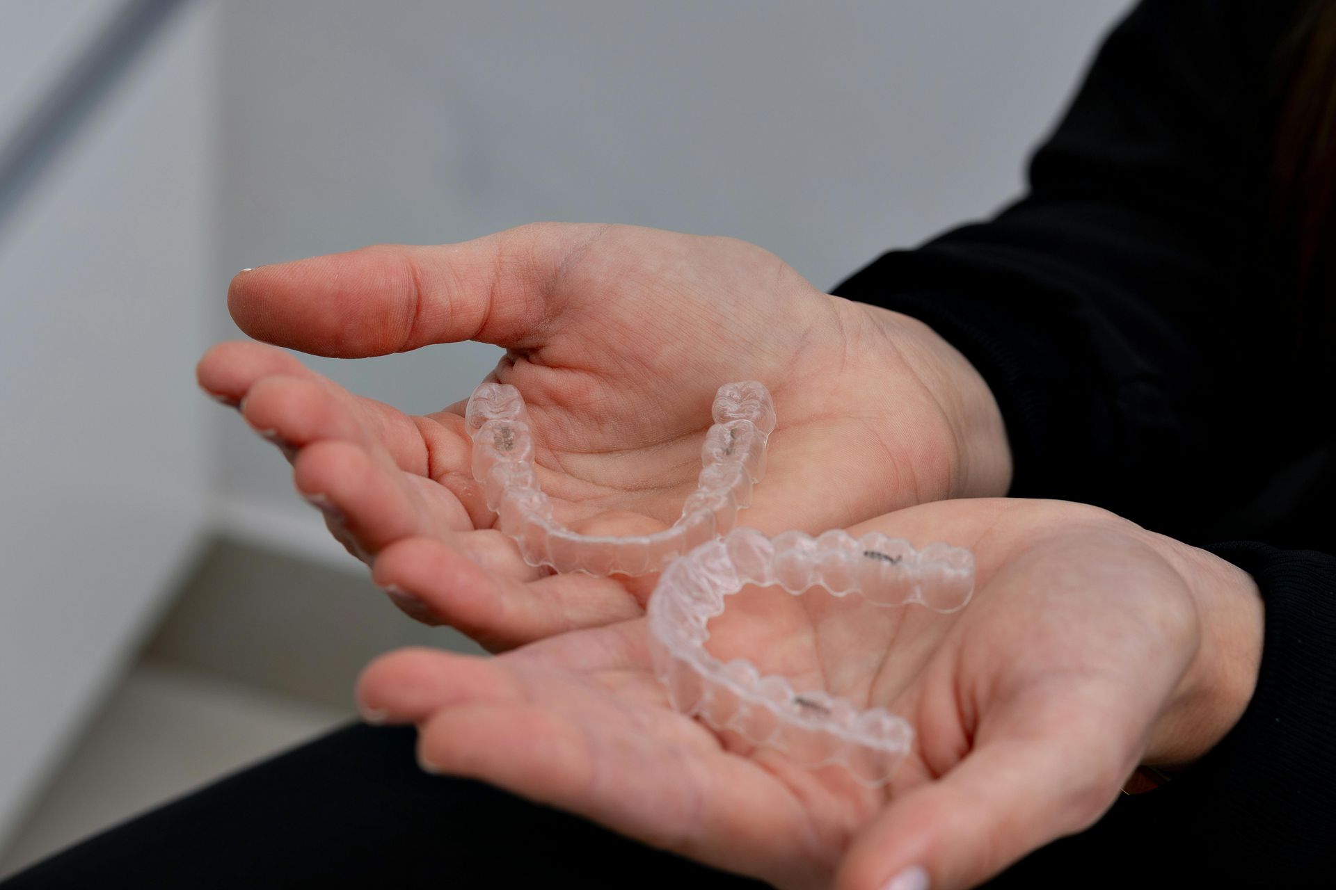 A person is holding two clear braces in their hands.