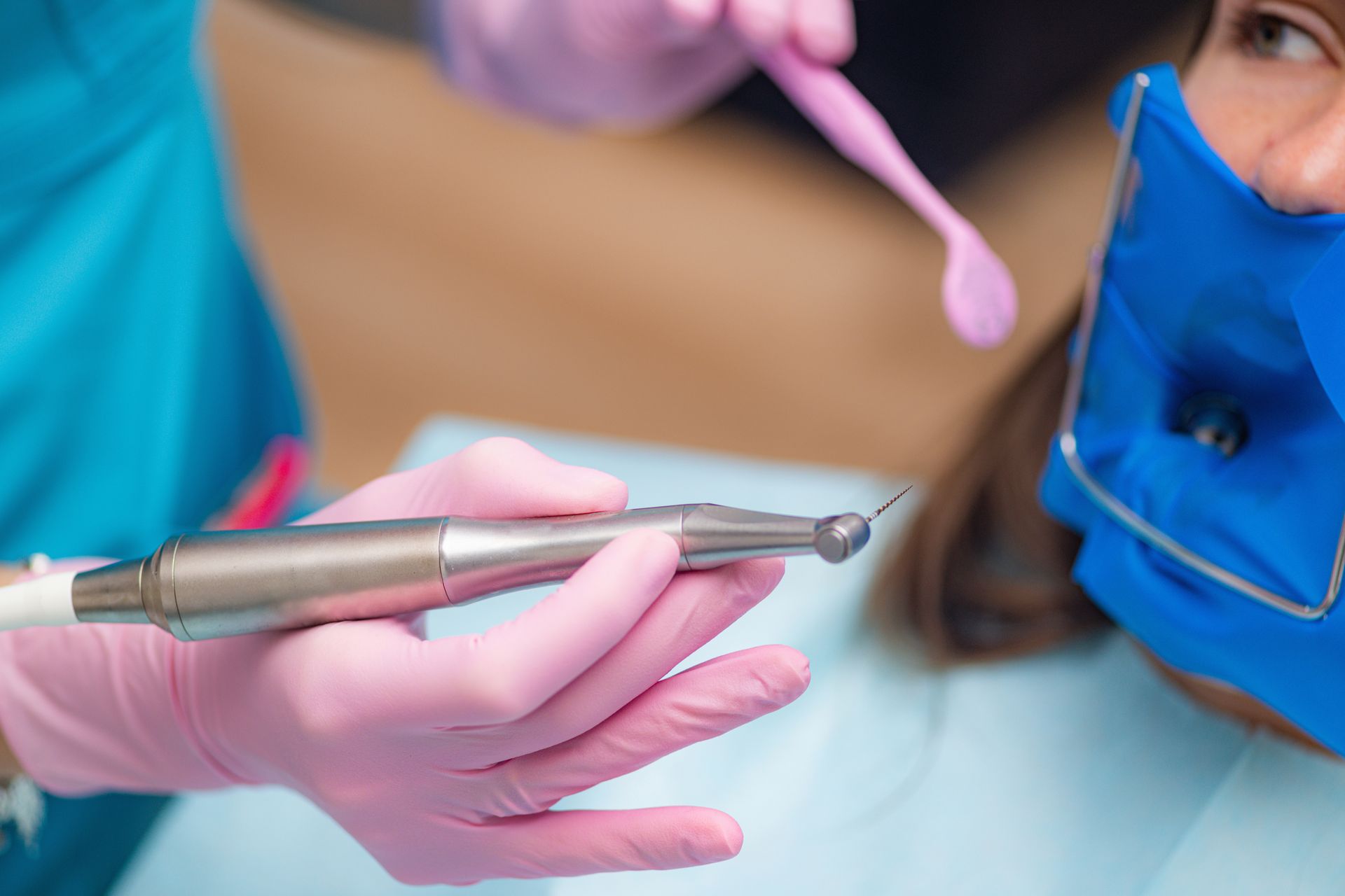 A dentist is using a drill on a patient 's teeth.