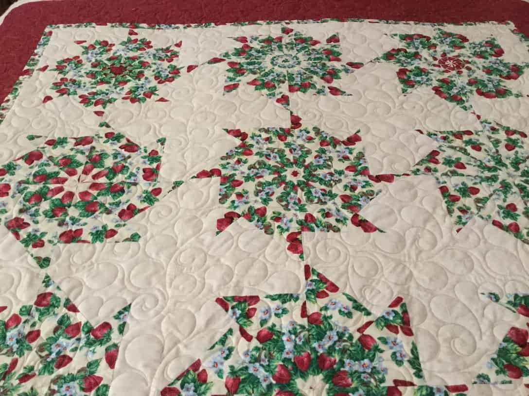 Quilt With White Background and Repeating Red and Green Floral Star Patterns — Morning Star Quilting in Bateau Bay, NSW