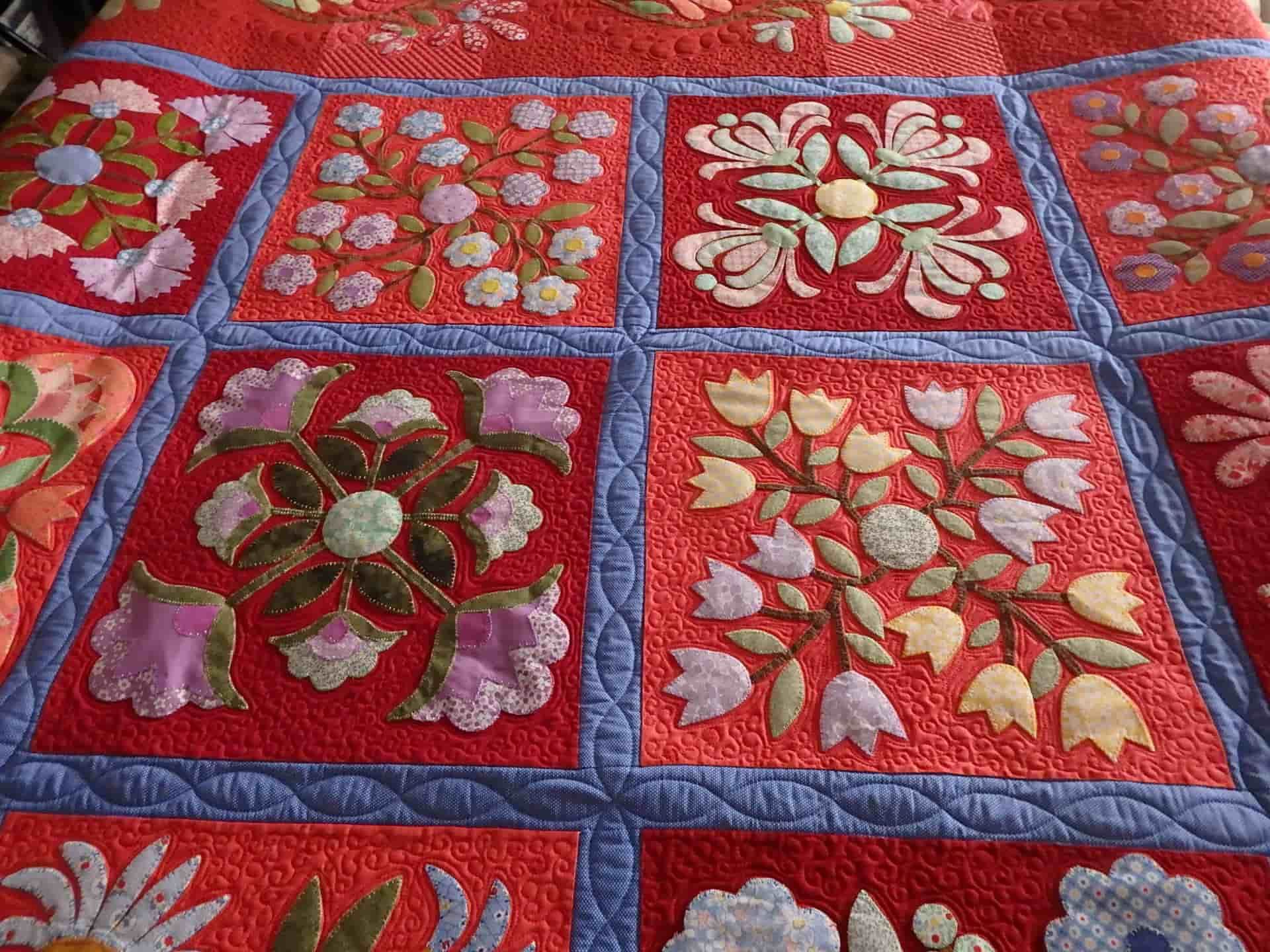 Quilted Red Fabric With Floral Appliqued Squares, Blue Border — Morning Star Quilting in Bateau Bay, NSW