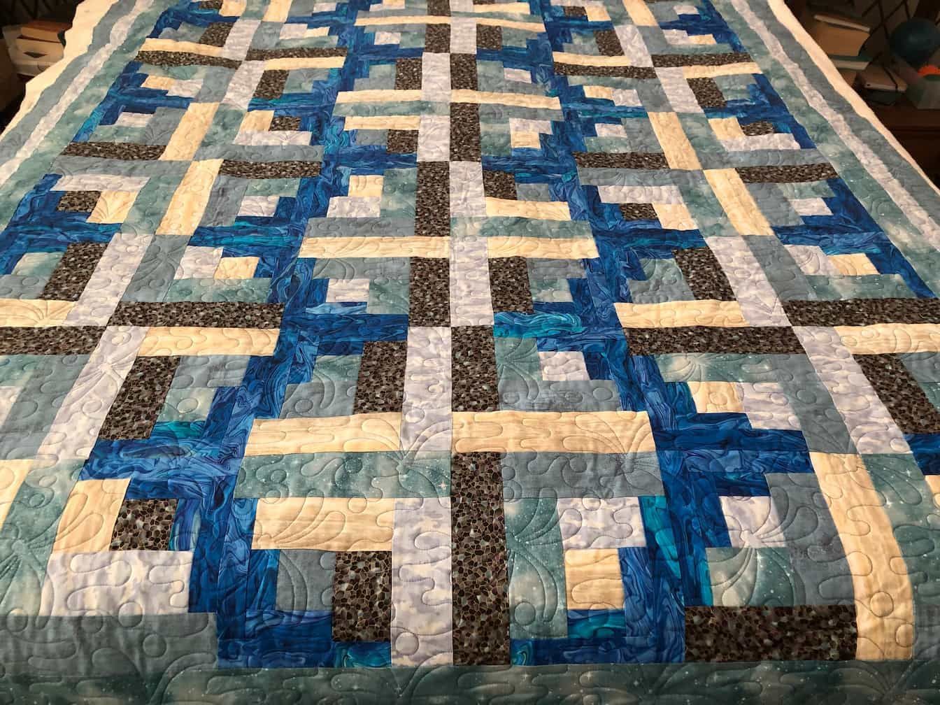 Blue, Teal, and Cream Quilt With Geometric Block Pattern on a Bed — Morning Star Quilting in Bateau Bay, NSW