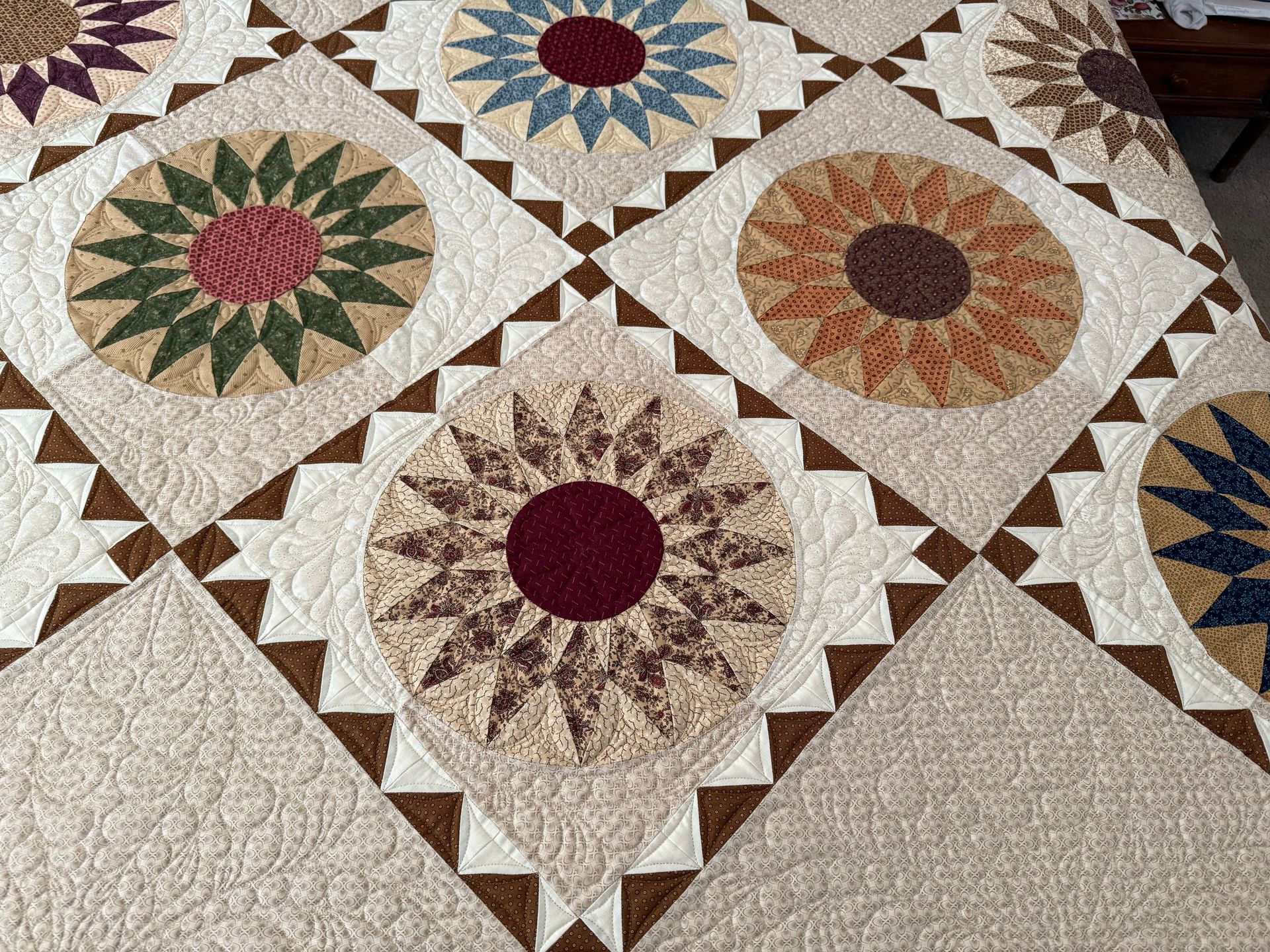 Quilt with repeating circular starburst patterns in various colours against a light beige background — Morning Star Quilting in Bateau Bay, NSW