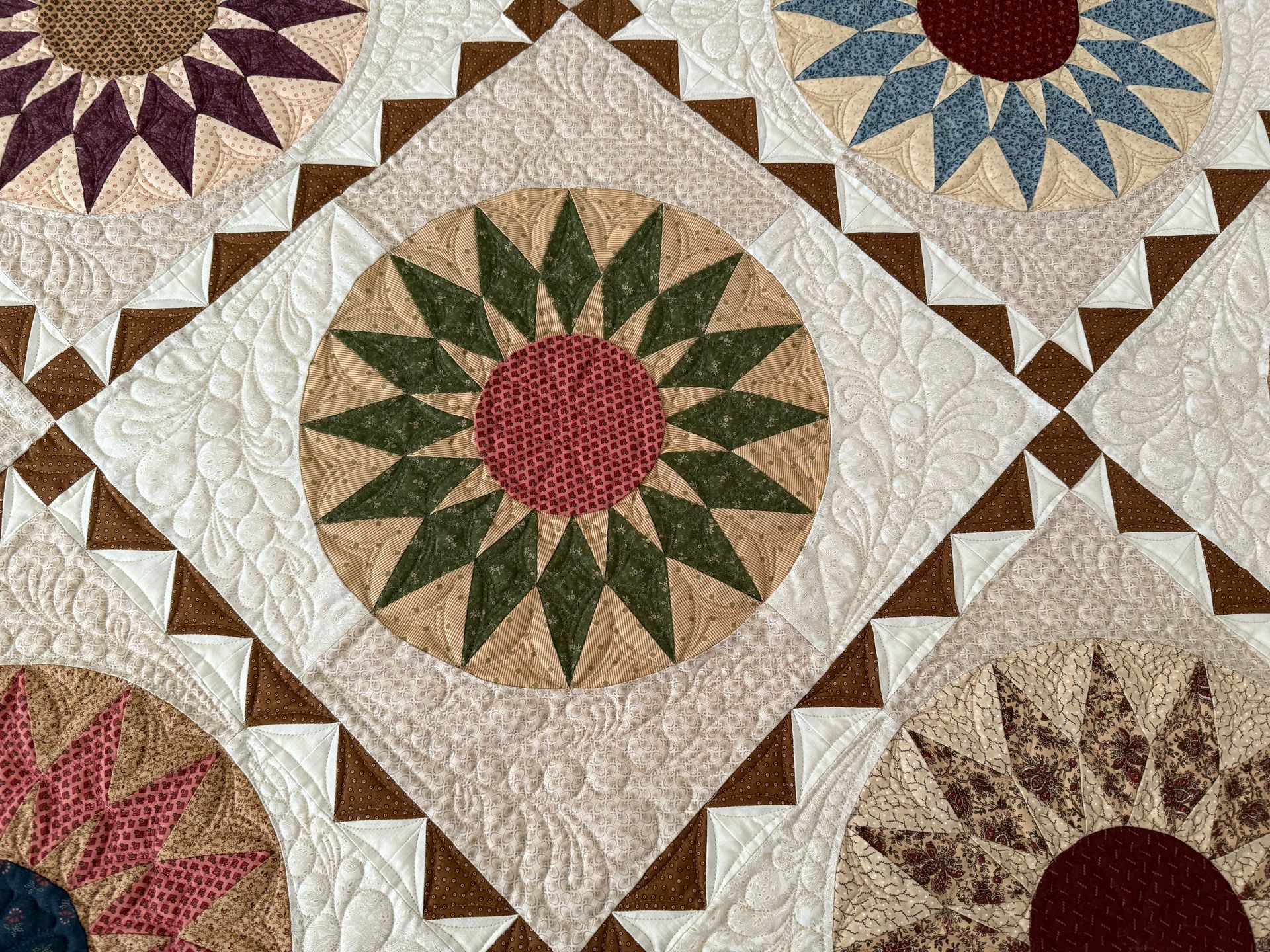 Close-up of a quilt with circular floral designs, in shades of red, green, blue, brown, and cream — Morning Star Quilting in Bateau Bay, NSW