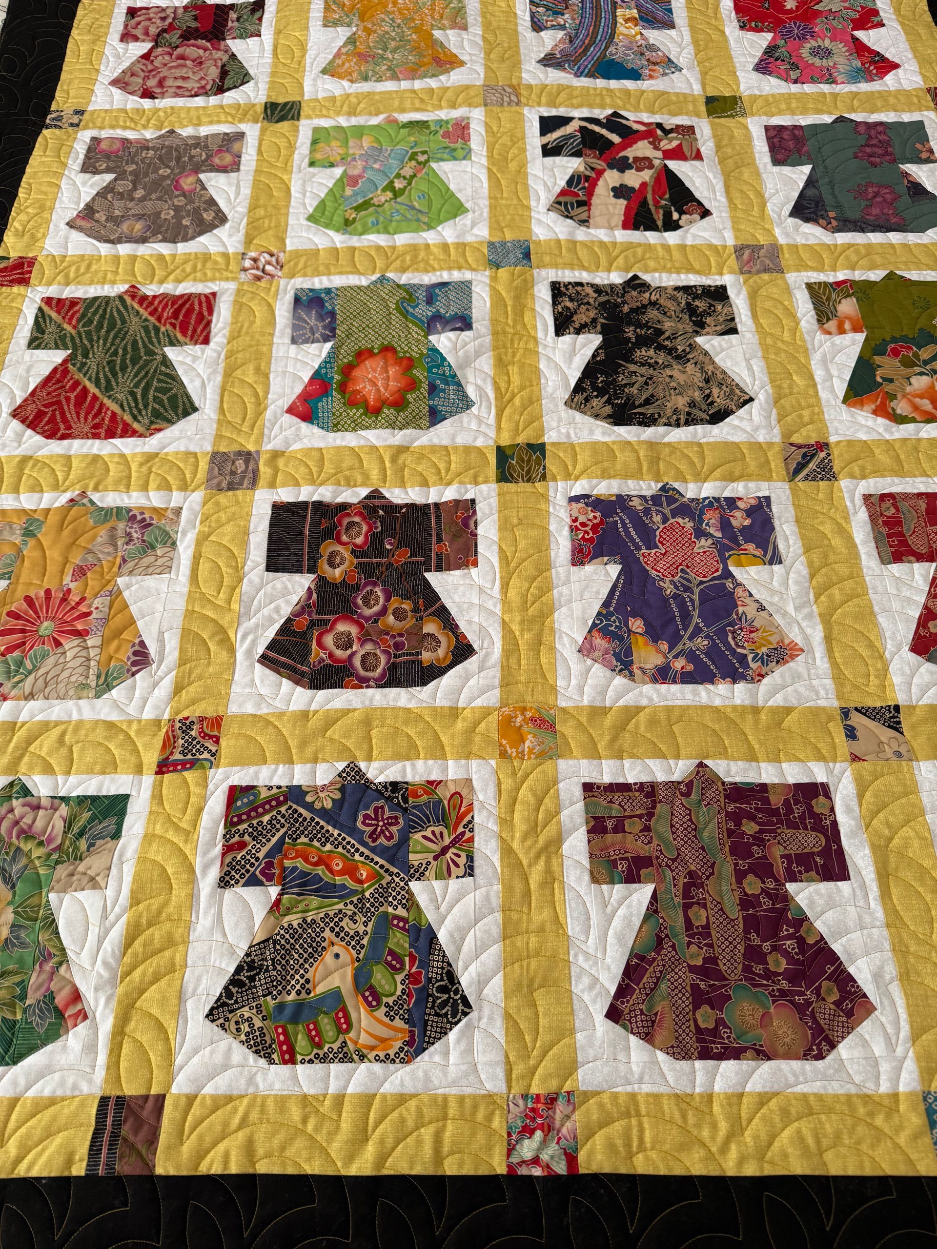 Quilt with kimono-shaped blocks in various patterned fabrics set against a yellow grid — Morning Star Quilting in Bateau Bay, NSW