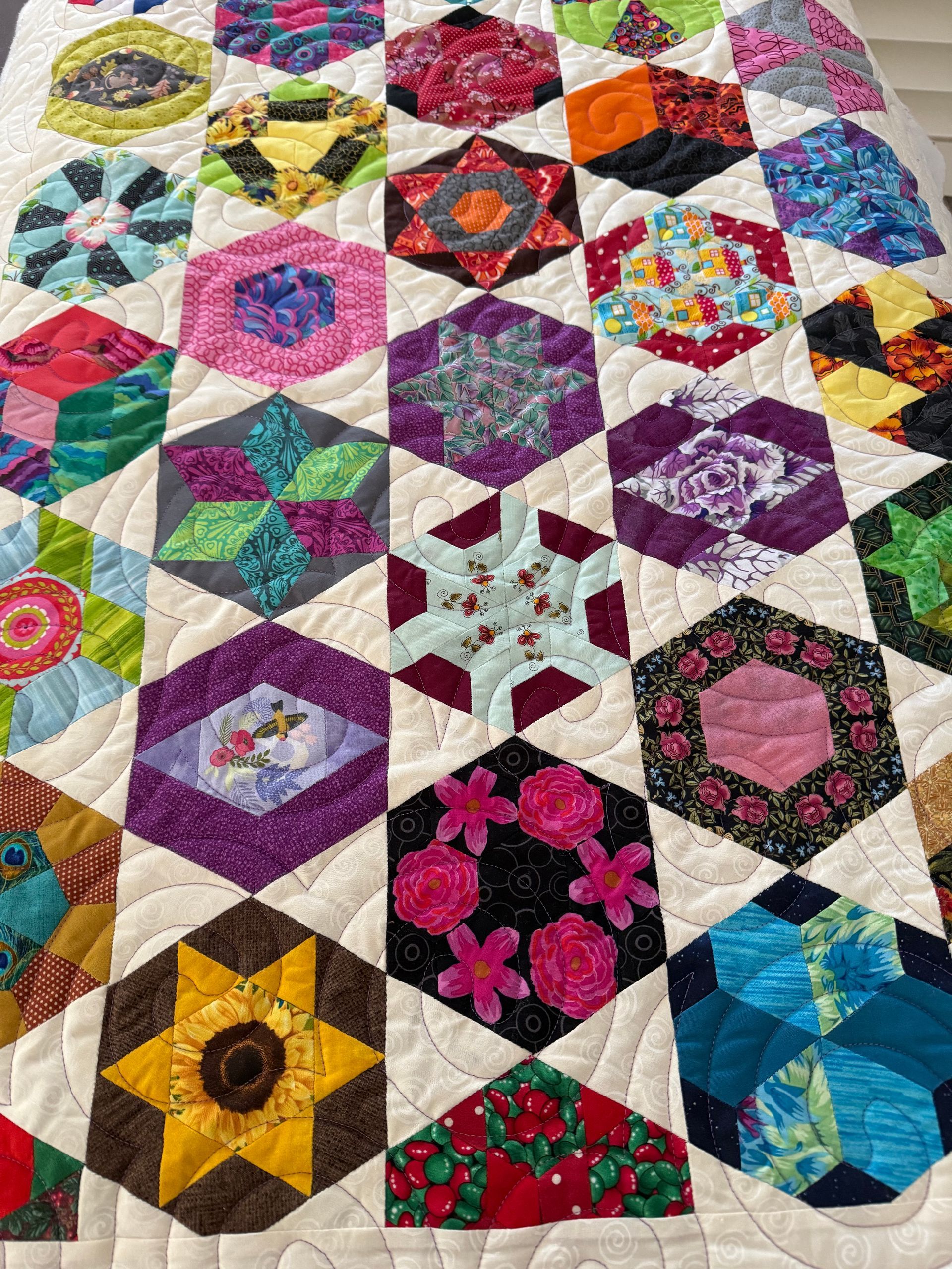 Close-up of a colourful hexagon quilt with various patterned fabric blocks and light-coloured quilting — Morning Star Quilting in Bateau Bay, NSW