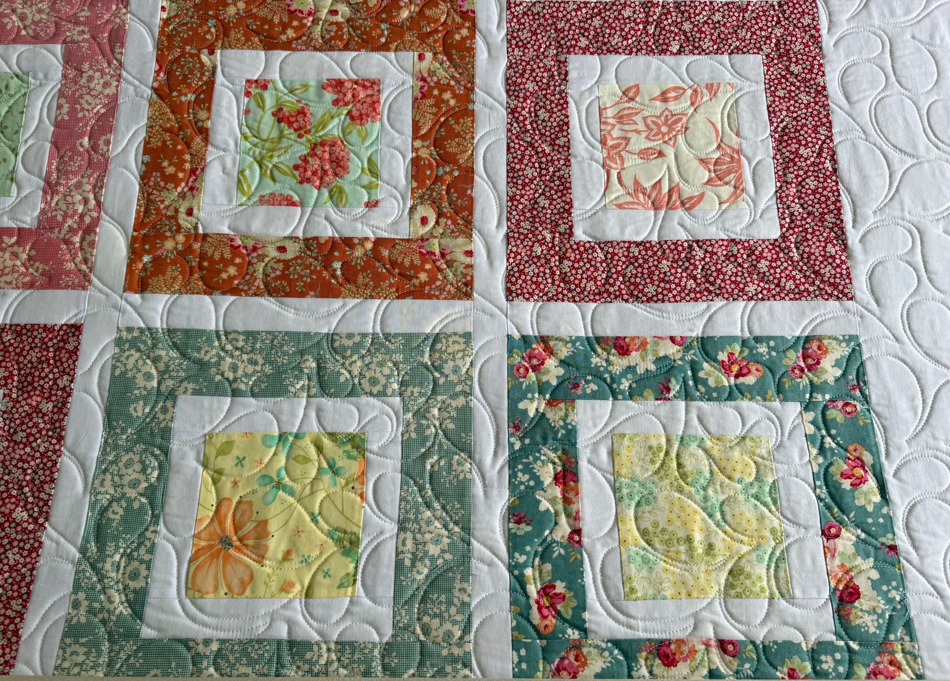 Quilt with square blocks, floral fabric centers and borders, white spacing, and quilted background — Morning Star Quilting in Bateau Bay, NSW