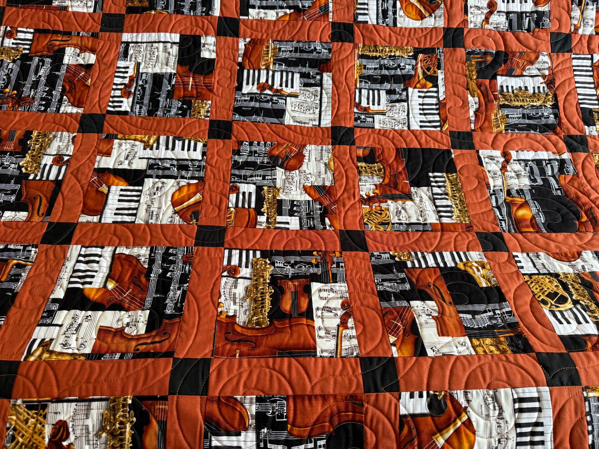 Quilt with musical instrument fabric in squares, framed with brown and black, showing detailed quilting — Morning Star Quilting in Bateau Bay, NSW