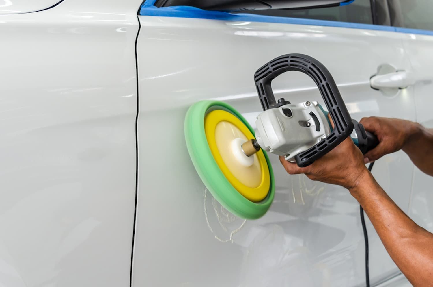 A Man Is Polishing a White Car with A Machine — Chinderah Smash Repairs in Chinderah, NSW