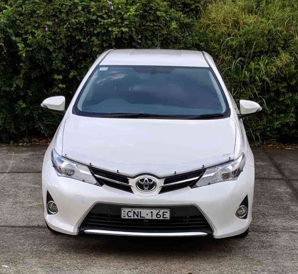 A White Toyota Car Is Parked In A Driveway — Chinderah Smash Repairs in Chinderah, NSW