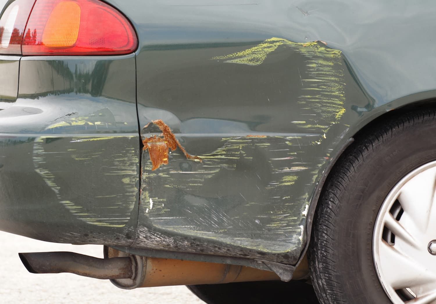 A Green Car with A Damaged Fender and Exhaust Pipe — Chinderah Smash Repairs in Chinderah, NSW
