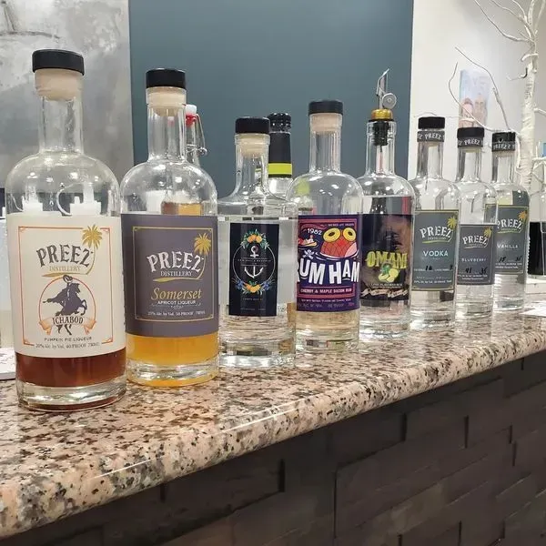 Bottles of alcohol, including Preez brand, line a bar counter. The bottles vary in color and label designs.