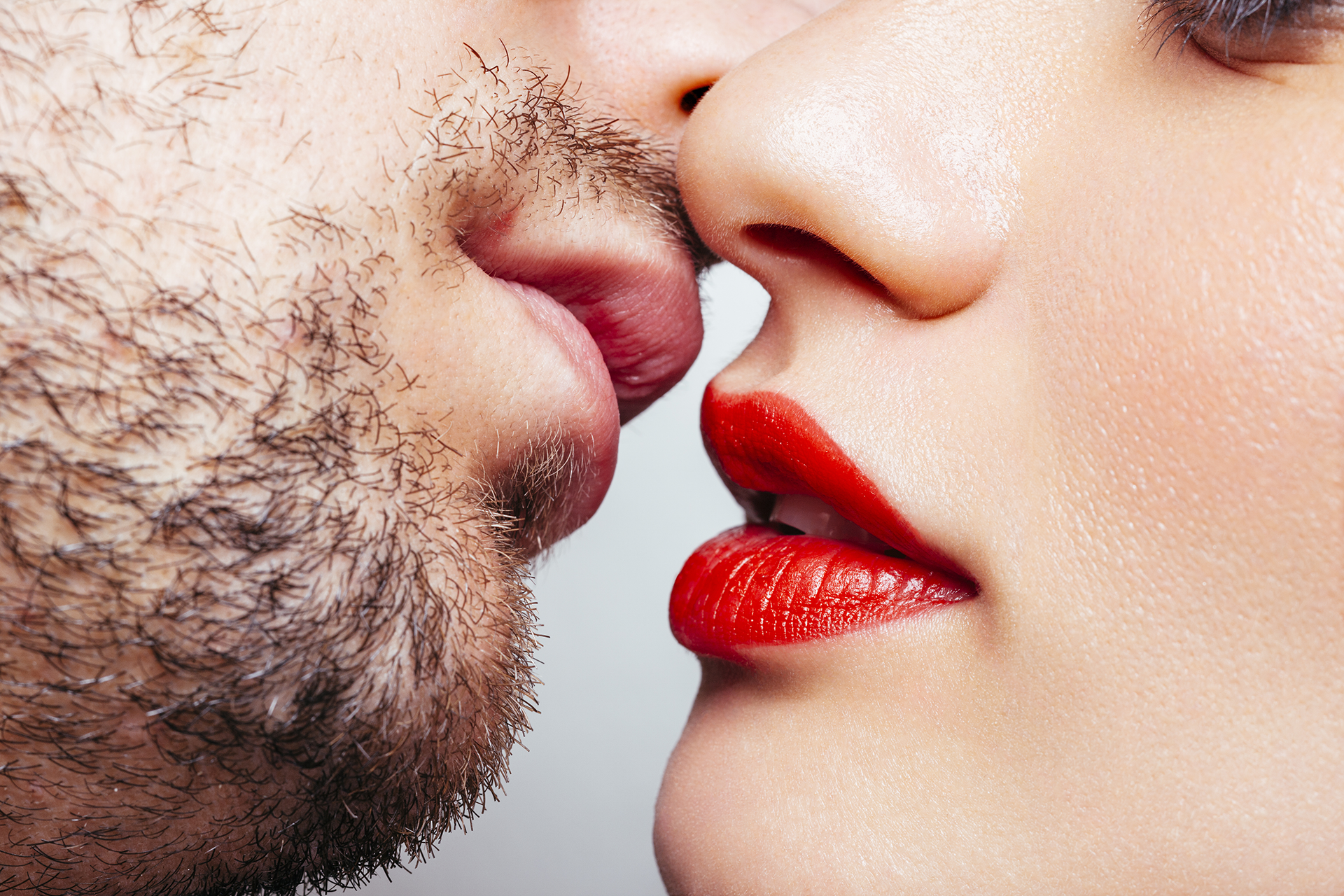 Close-up of a man and woman about to kiss. The woman wears red lipstick.