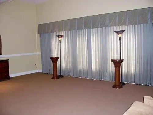 a living room with two lamps and curtains on the windows