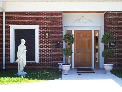 a brick building with a wooden door and a statue in front of it
