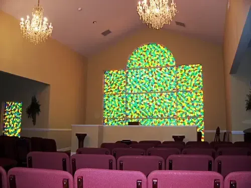an empty auditorium with pink seats and a stained glass window