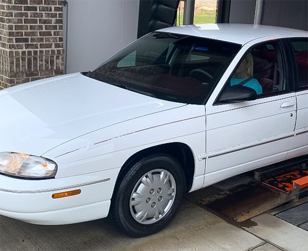 A white car is parked in front of a brick building